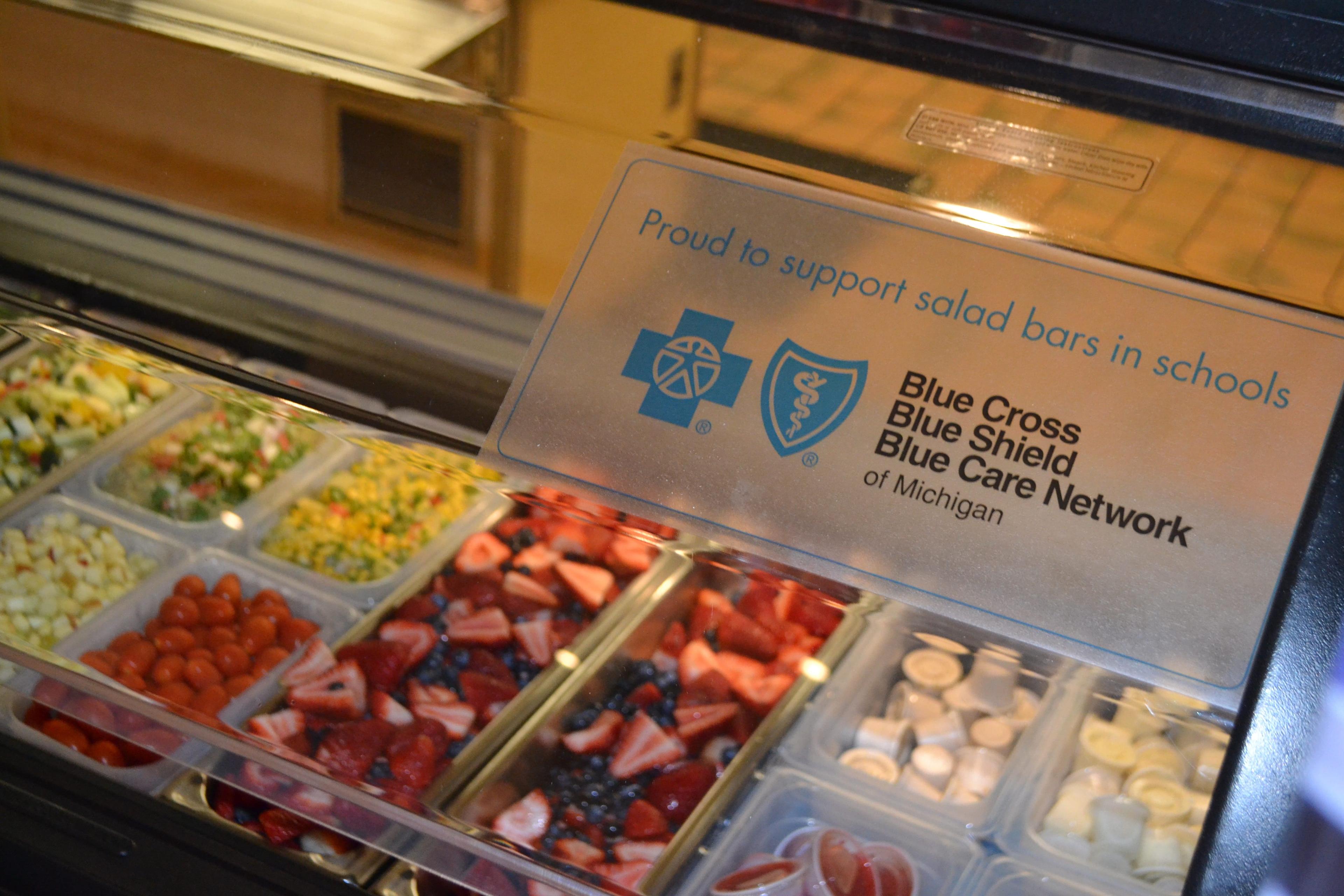 Image of a salad bar with sign that reads "Proud to support salad bars in schools" with the Blue Cross Blue Shield of Michigan and Blue Care Network logo