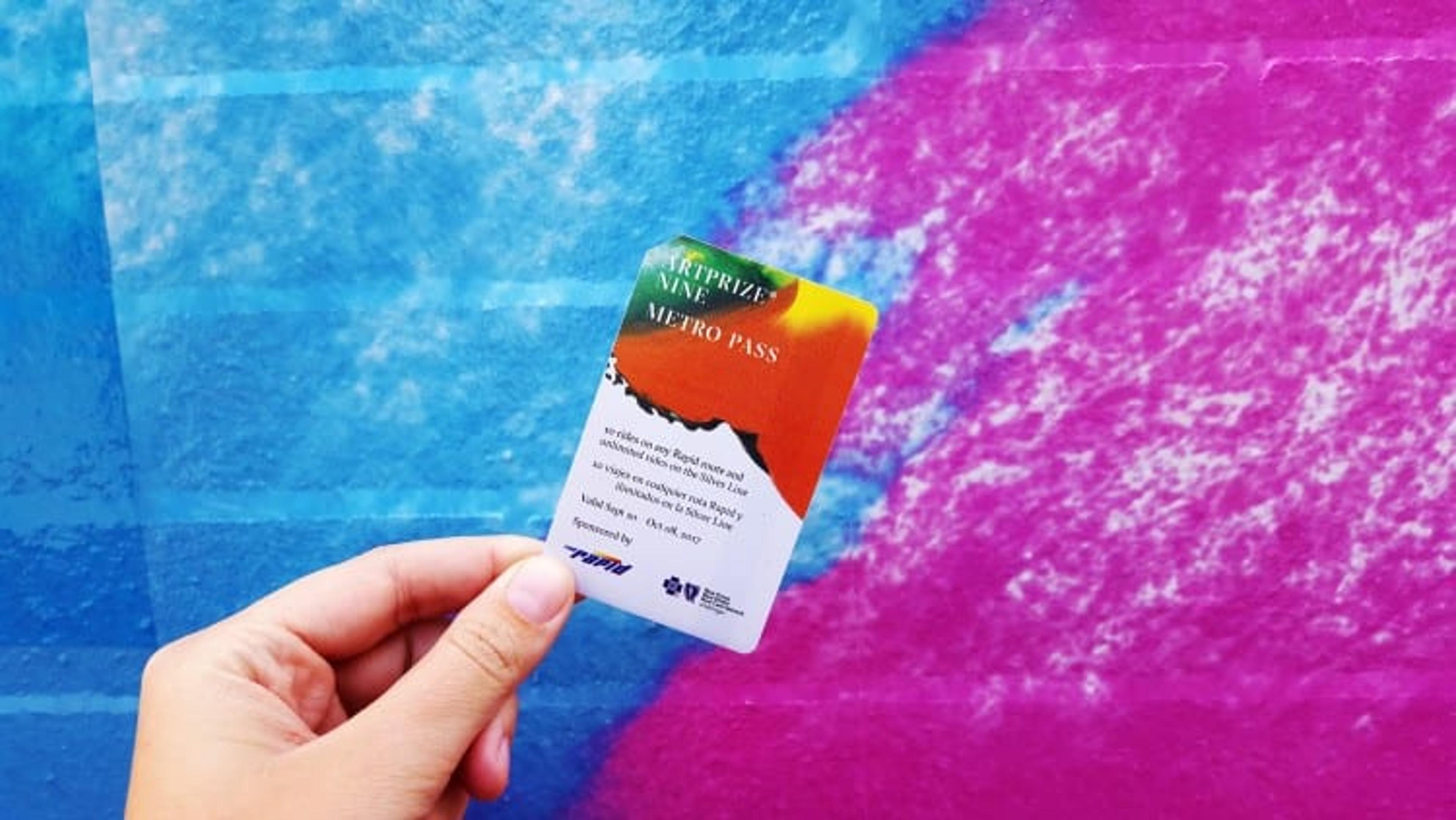 close up photo of a metro pass in front of a blue and pink background.