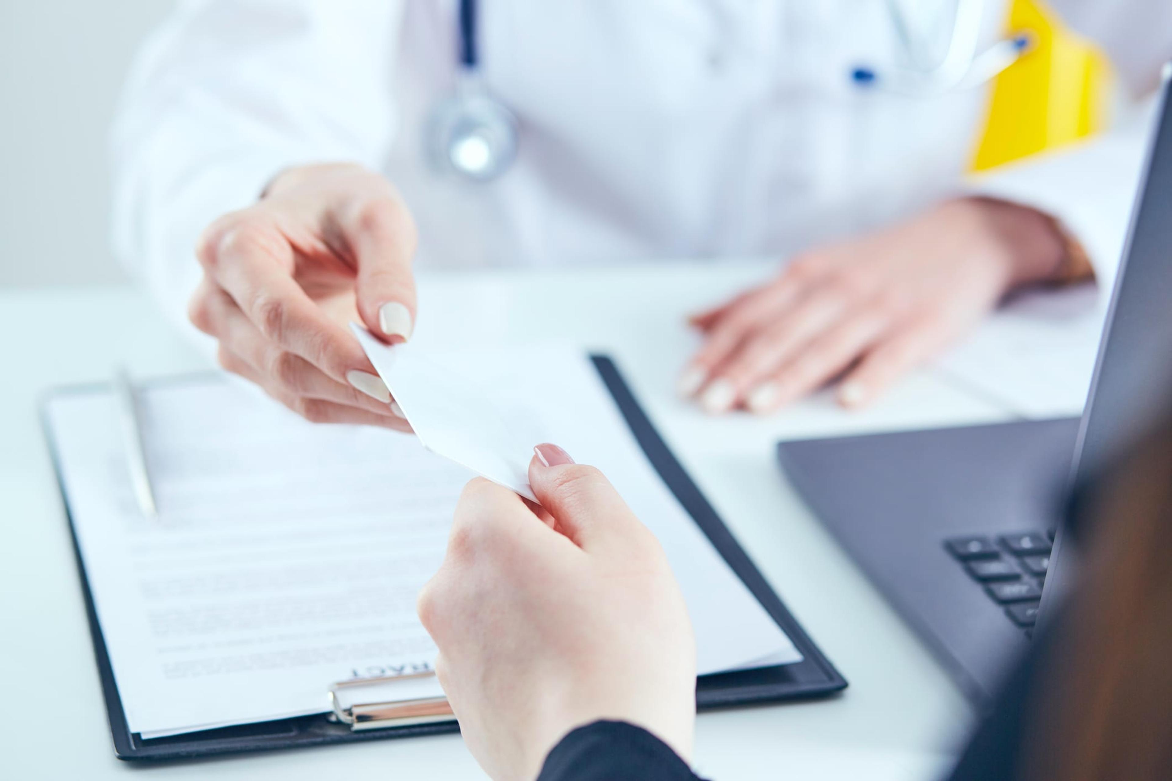 Health care professional hands over a medical card to a patient.