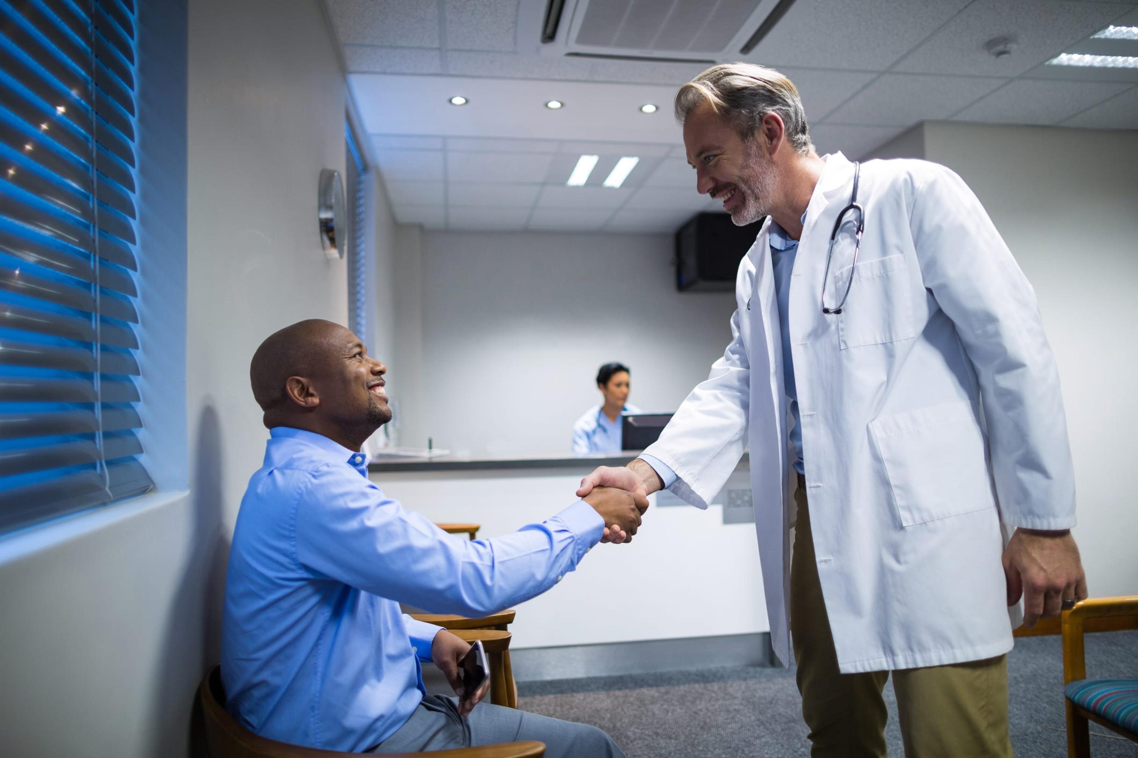 Male African-American patient shaking hands with his doctor.