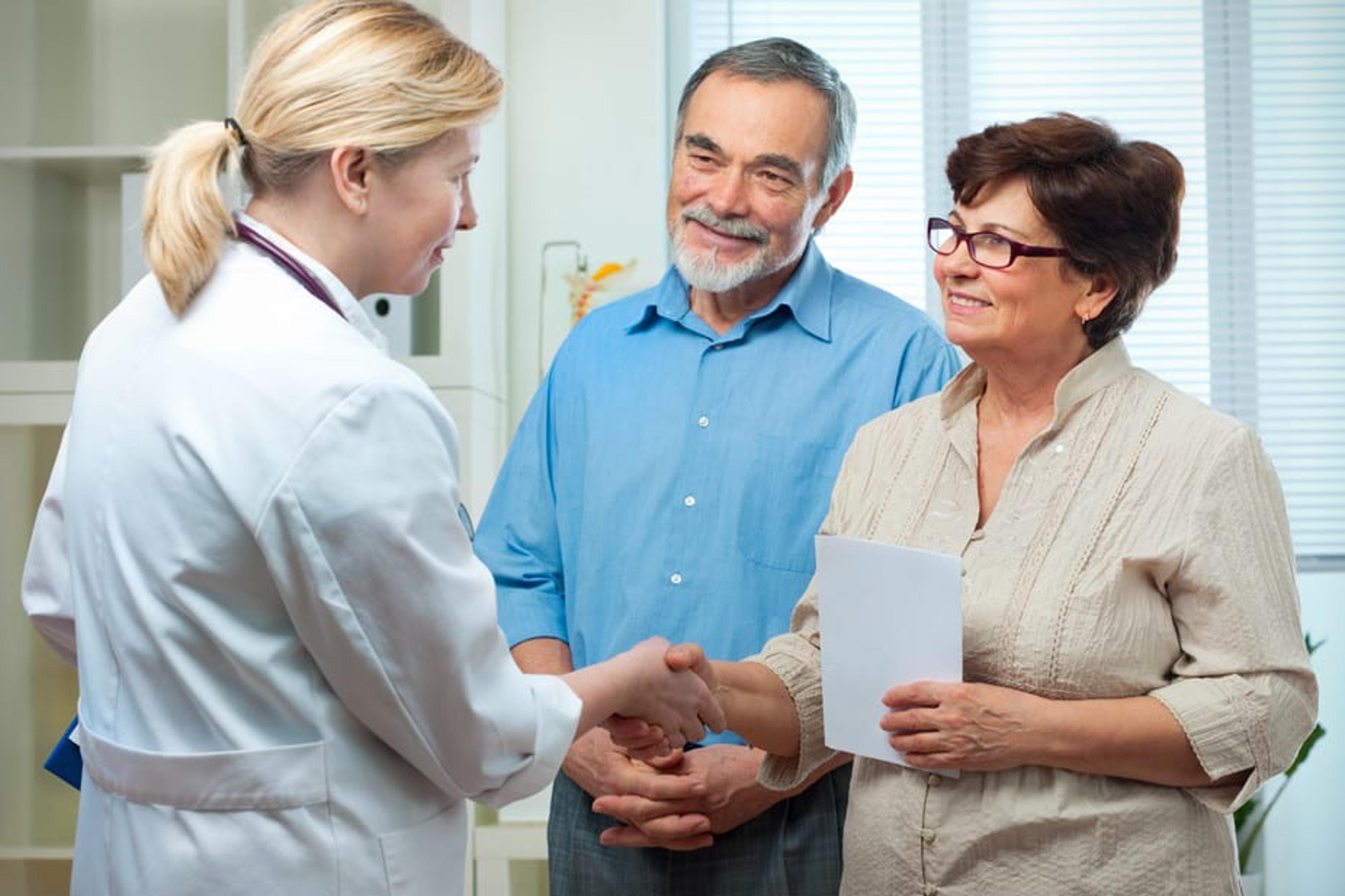 Older couple shaking hands with a female doctor