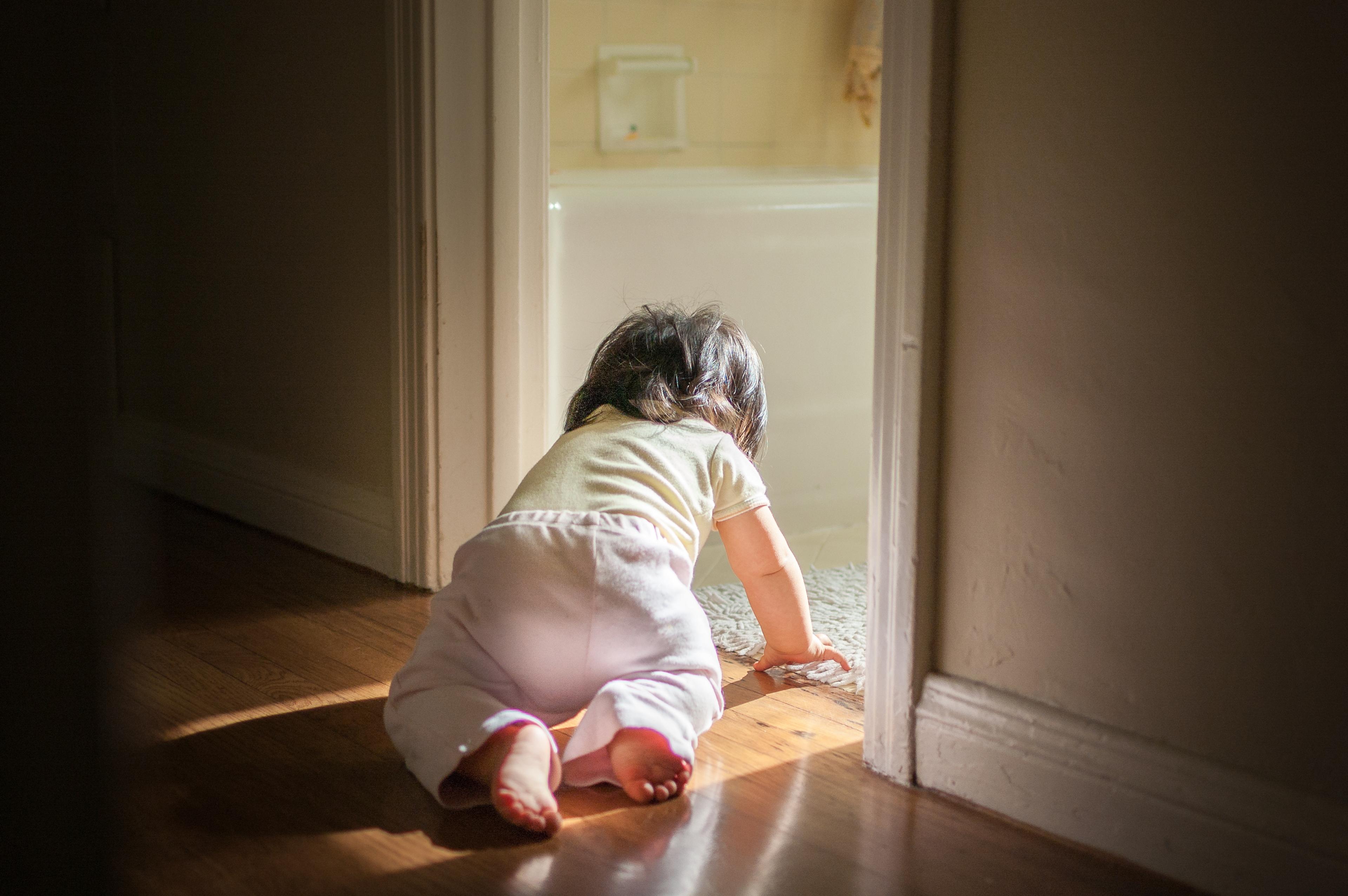 An unsupervised baby crawls into a bathroom.