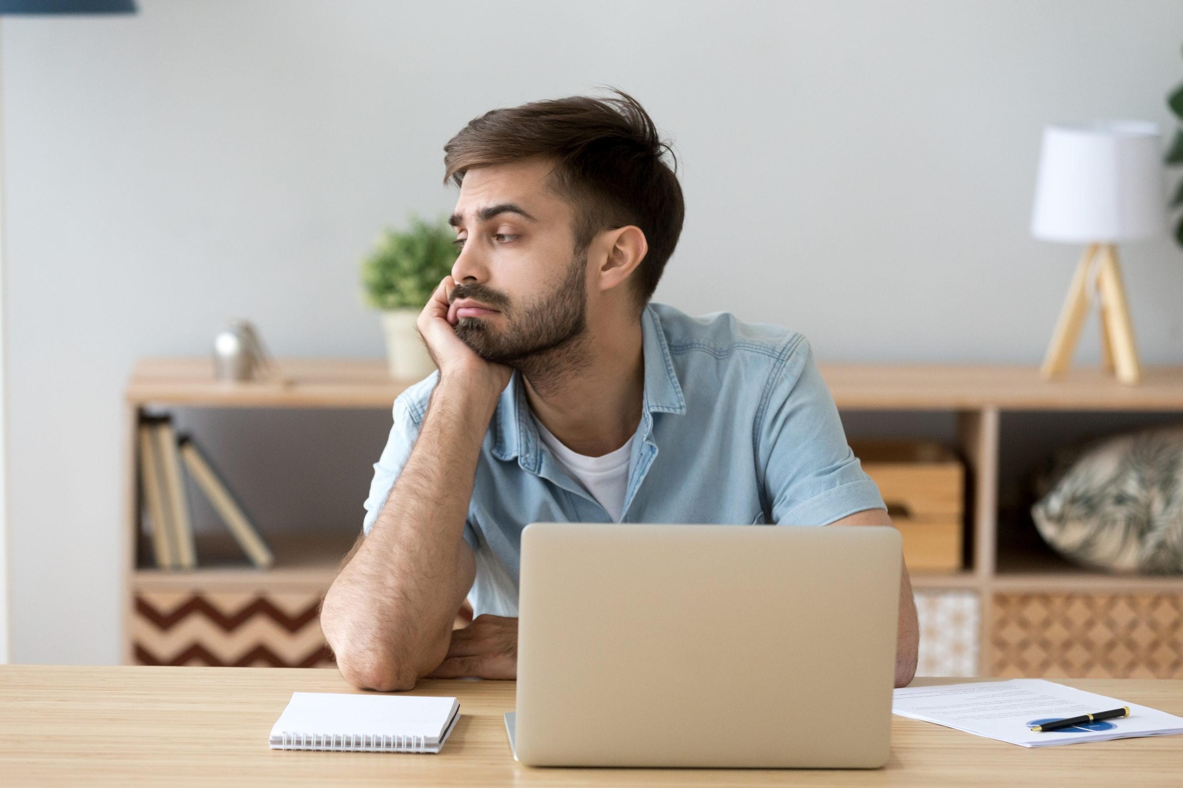 Young man in front of his computer staring into space