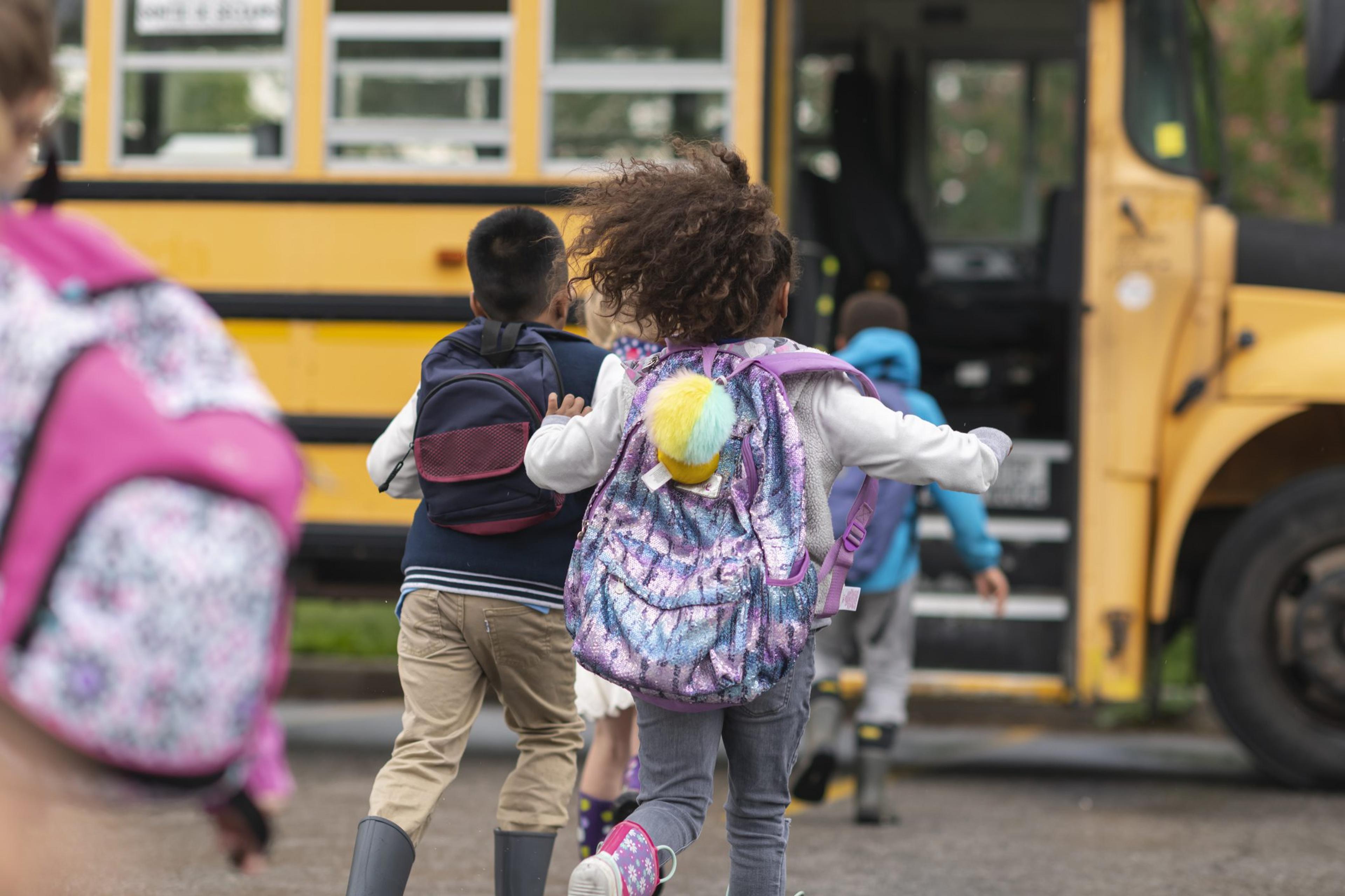 Elementary children get on a school bus