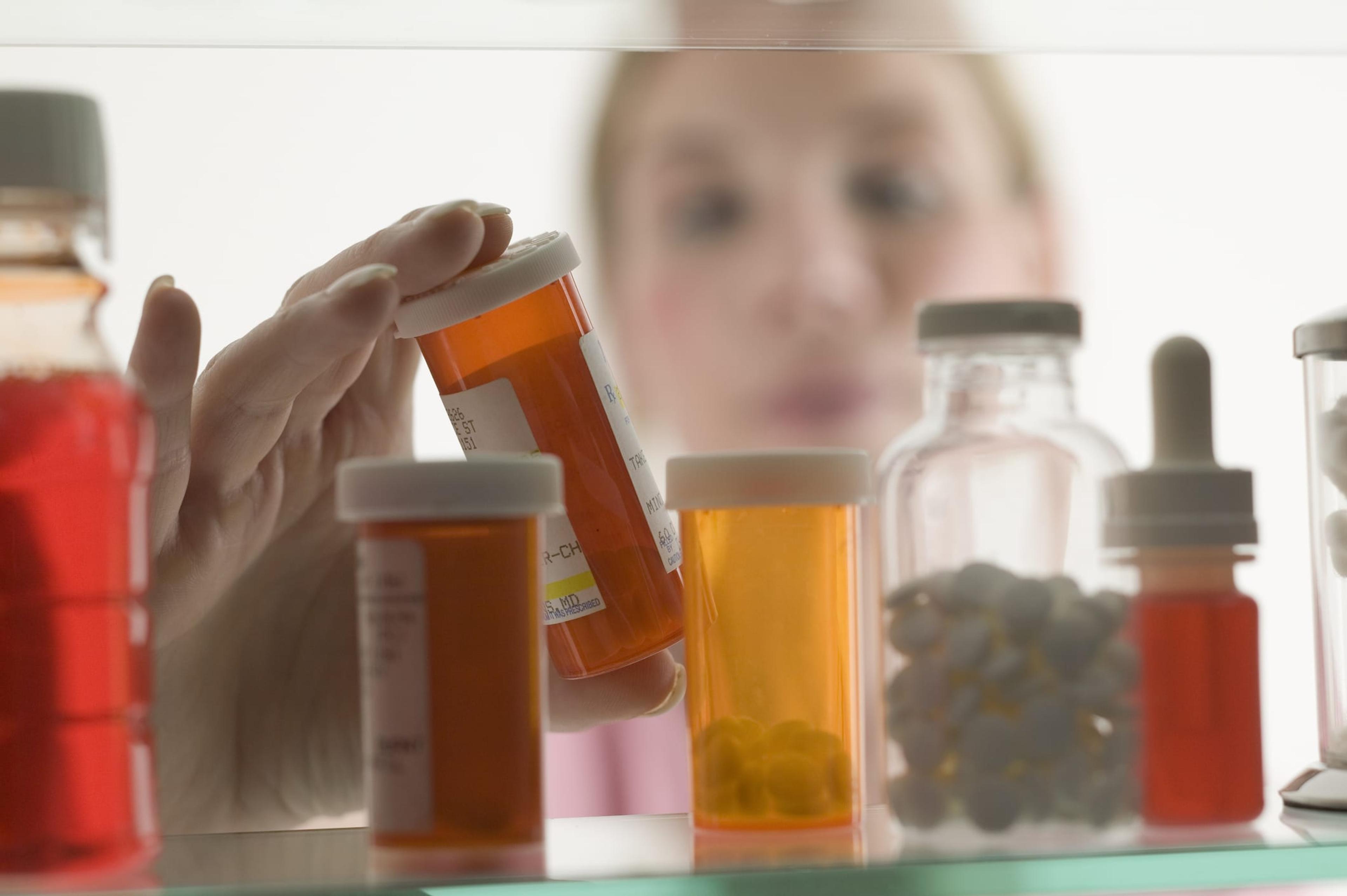 Person grabbing prescription pills from medicine cabinet