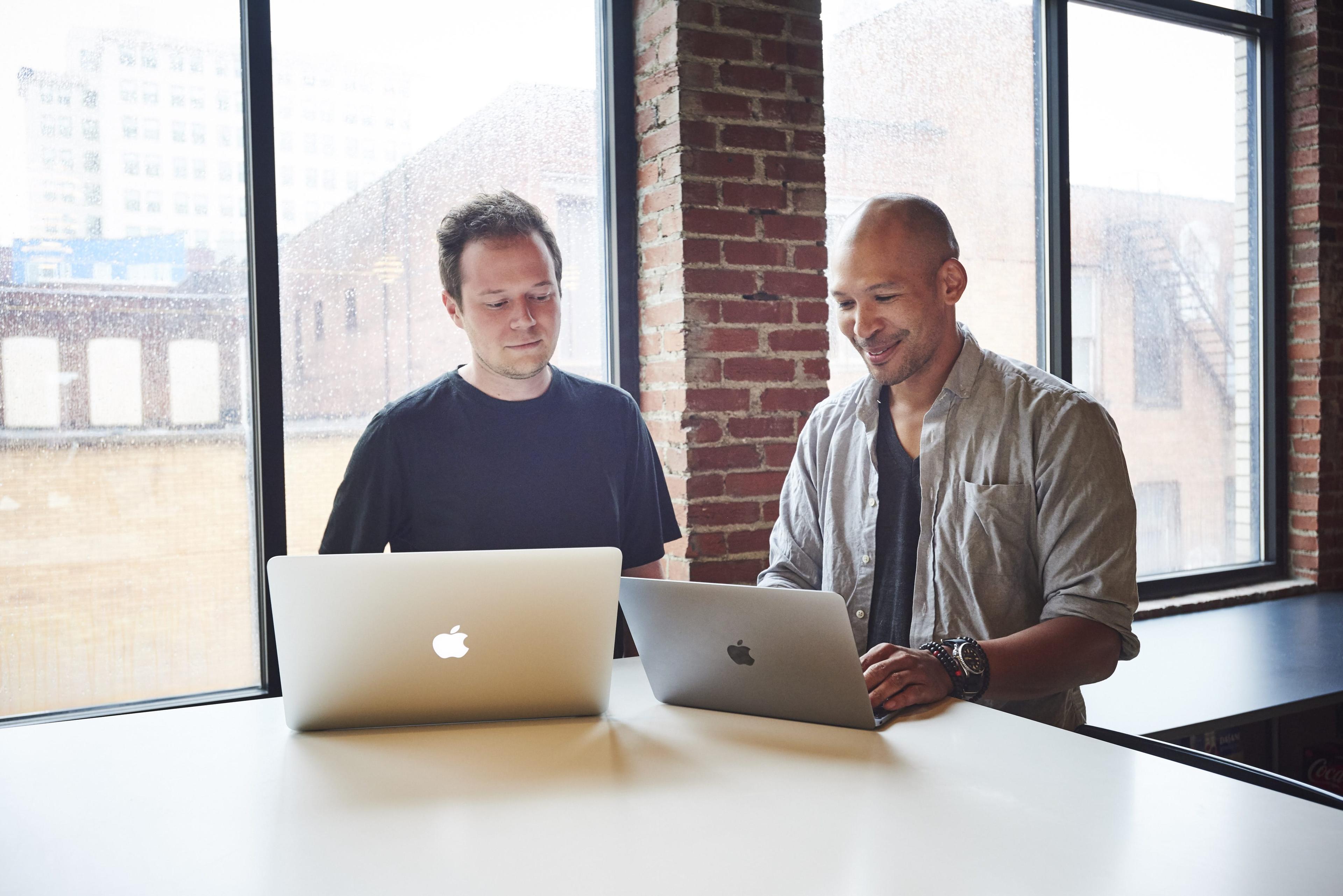 Two men standing and looking at computers