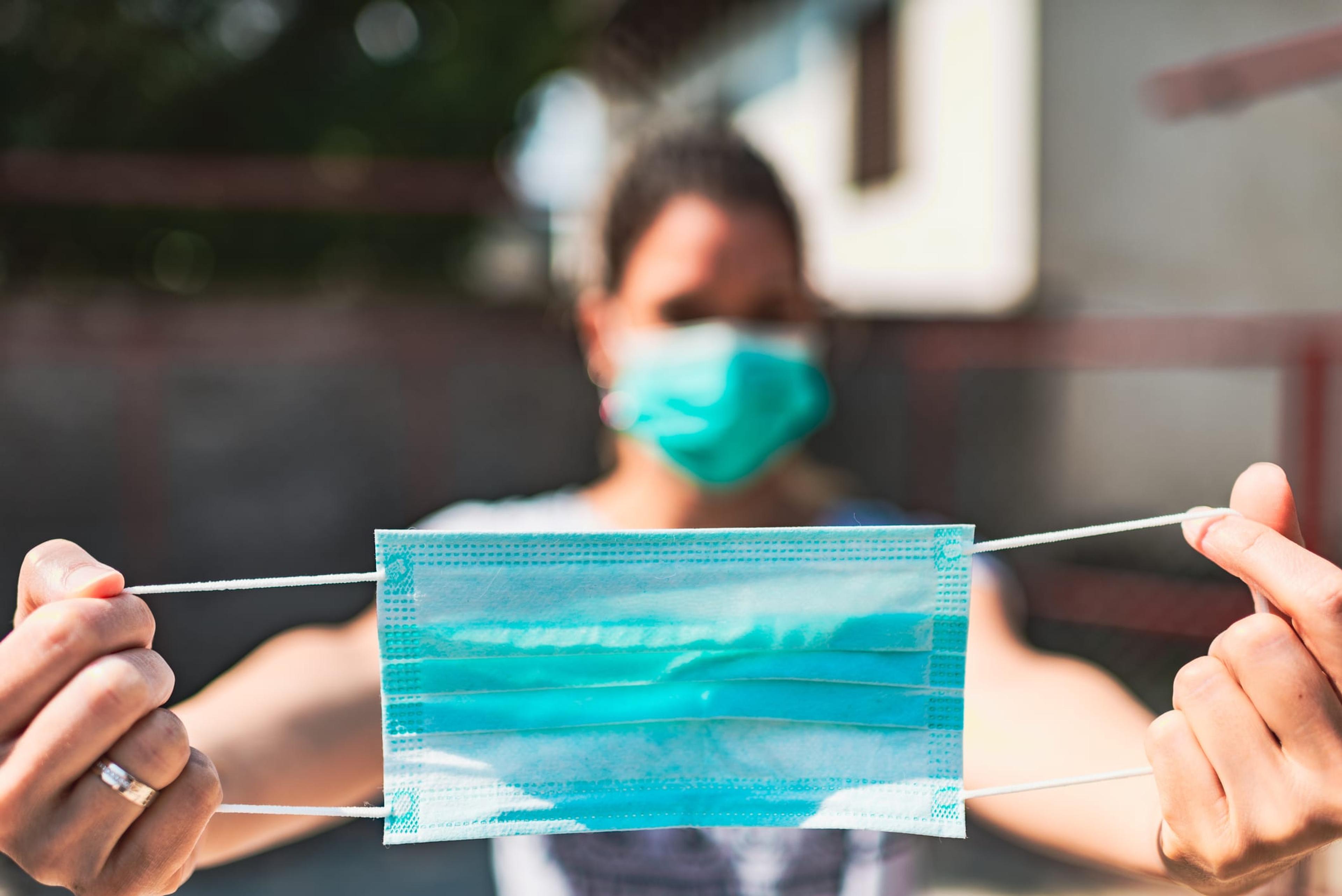 Woman wearing a mask hodling a second one