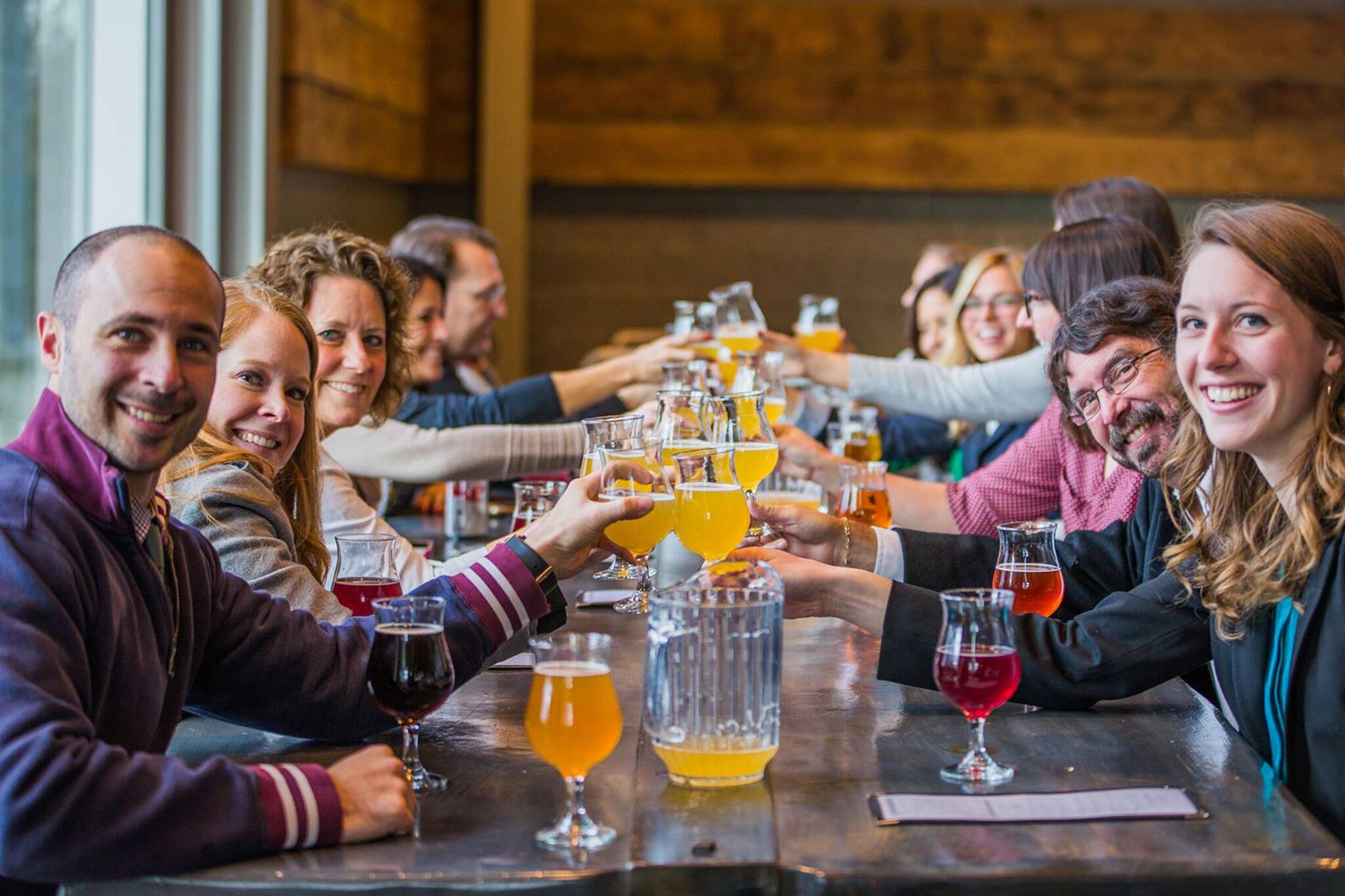 Friends at a long table with pitchers and glasses of beer.