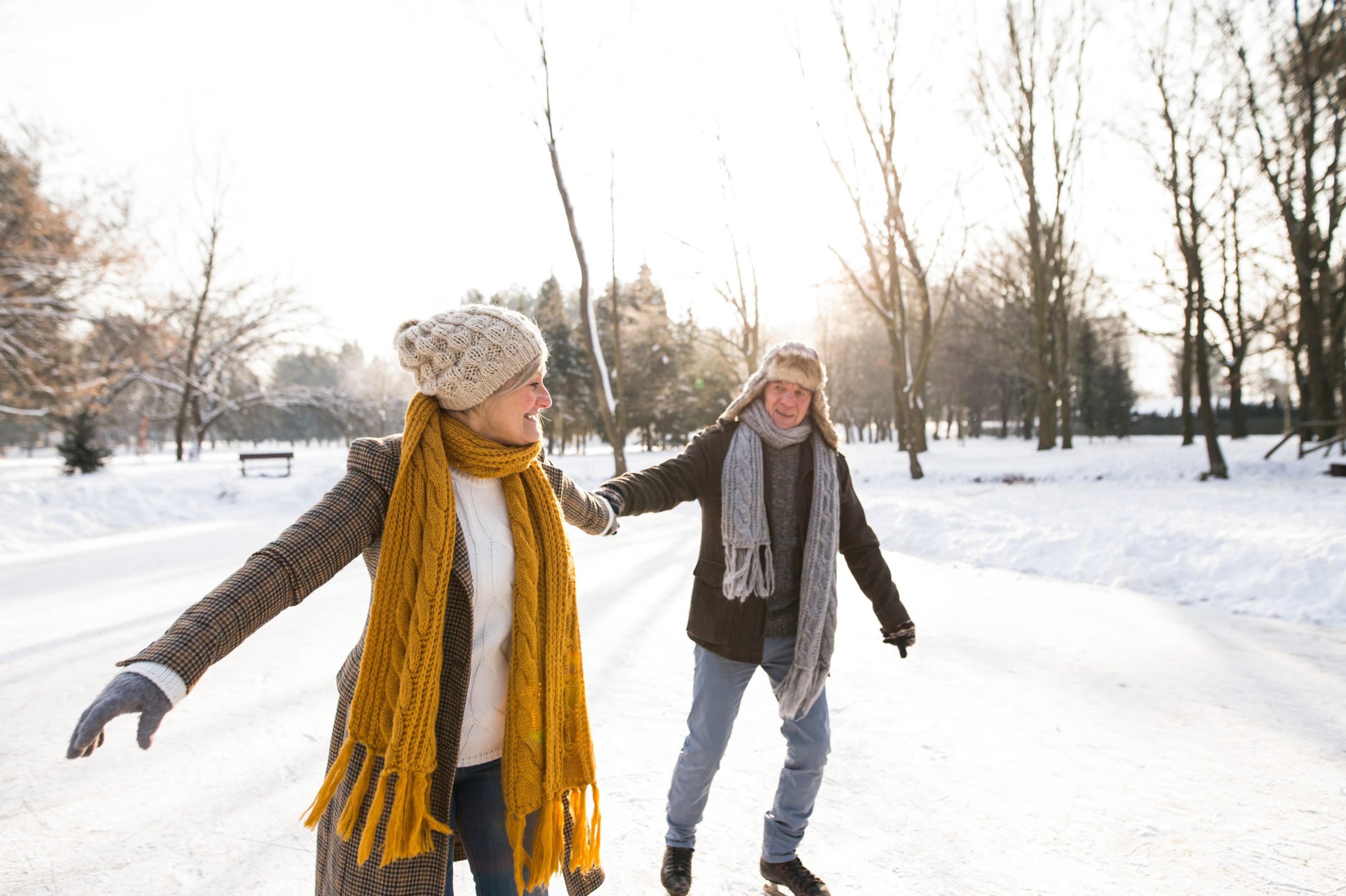 Beautiful senior woman and man in sunny winter nature ice skating.