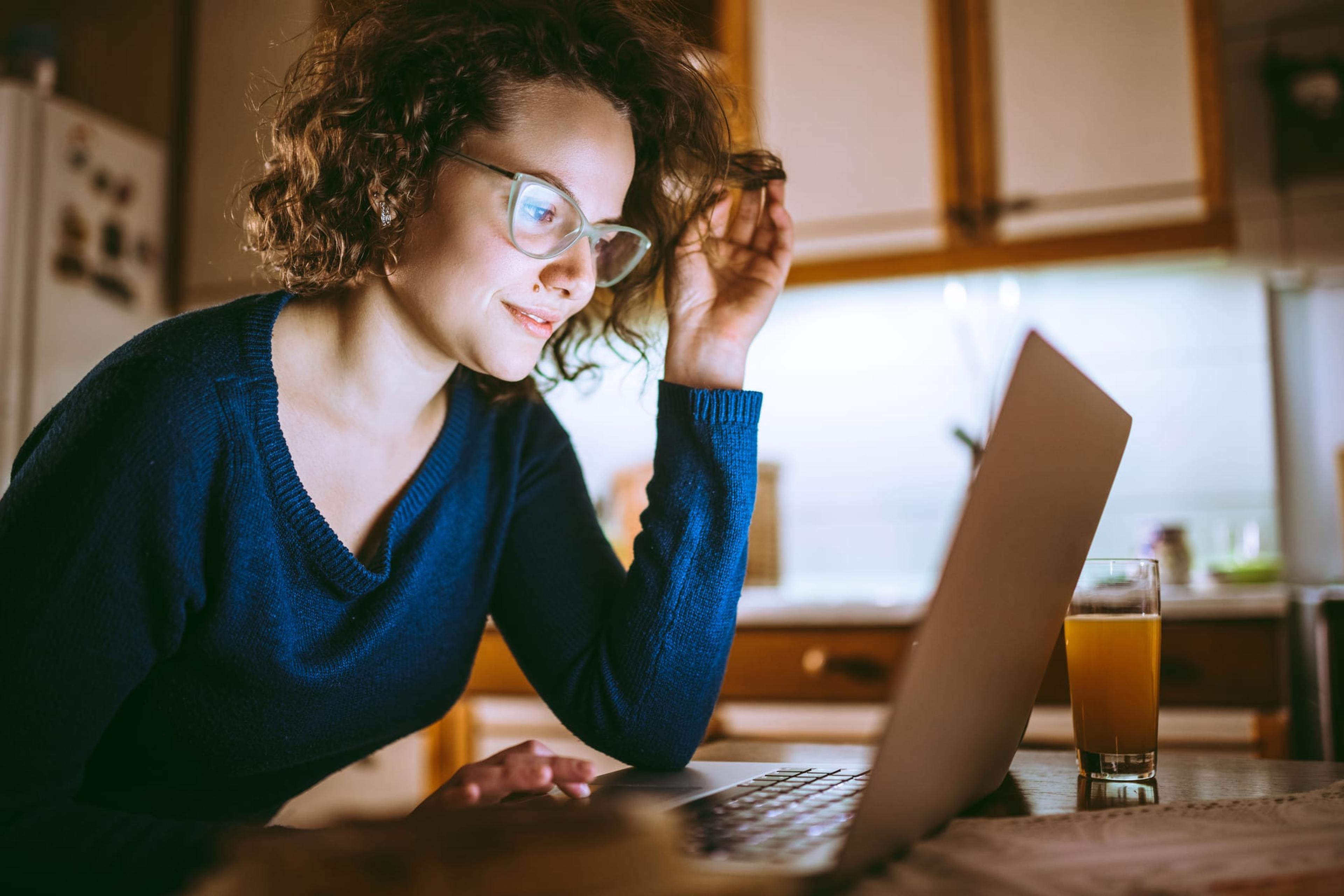 Young woman wearing glasses looks at her laptop