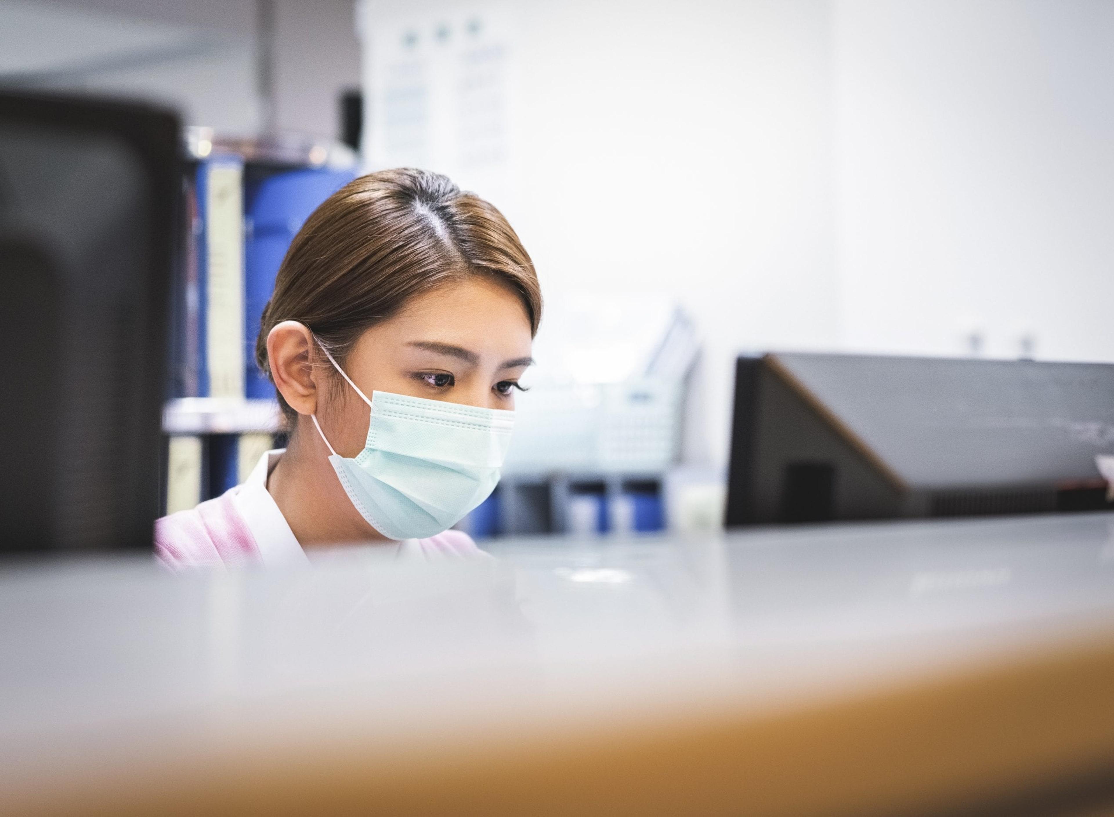 Nurse wearing a mask working on computer