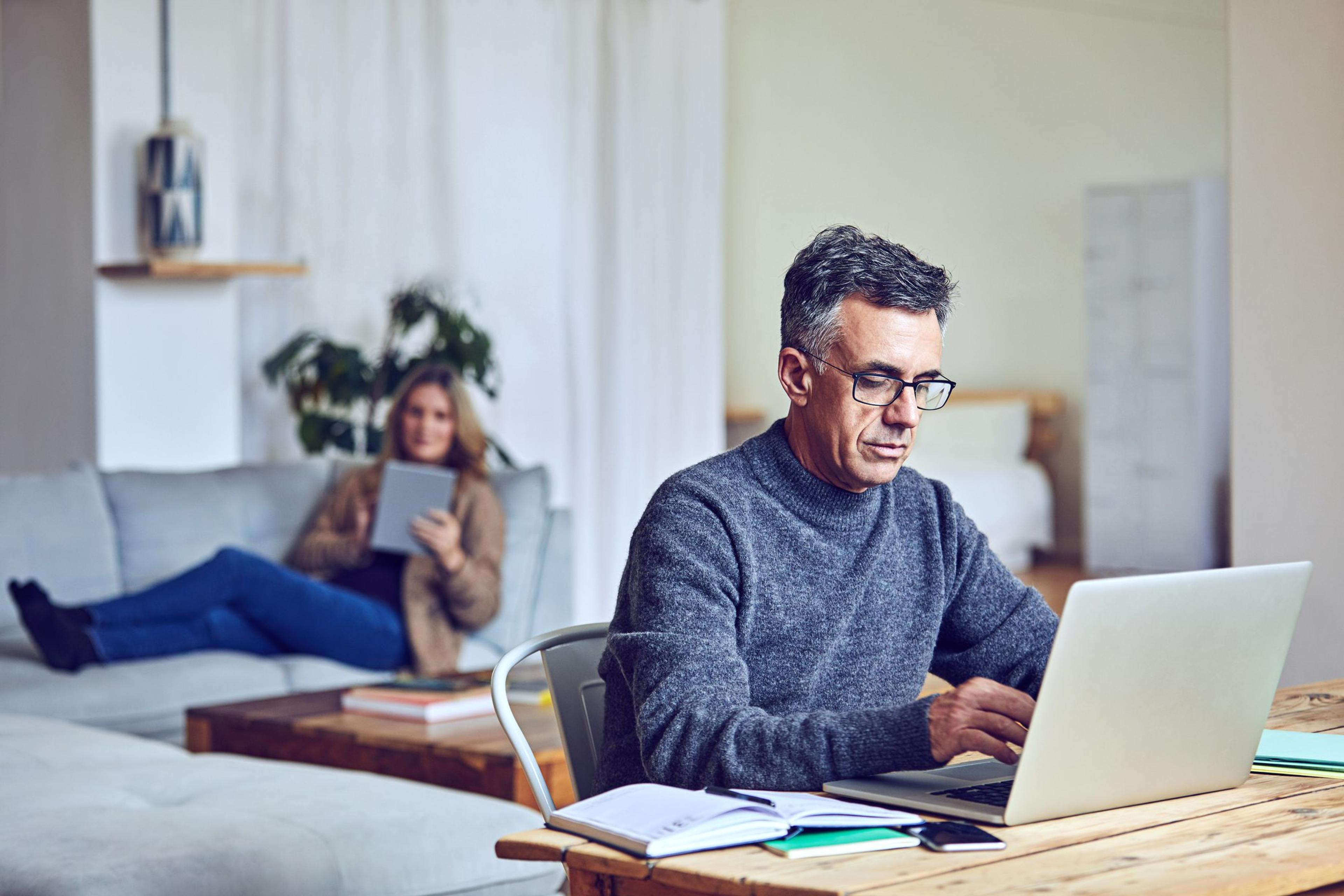 Senior man using a laptop at home with his wife