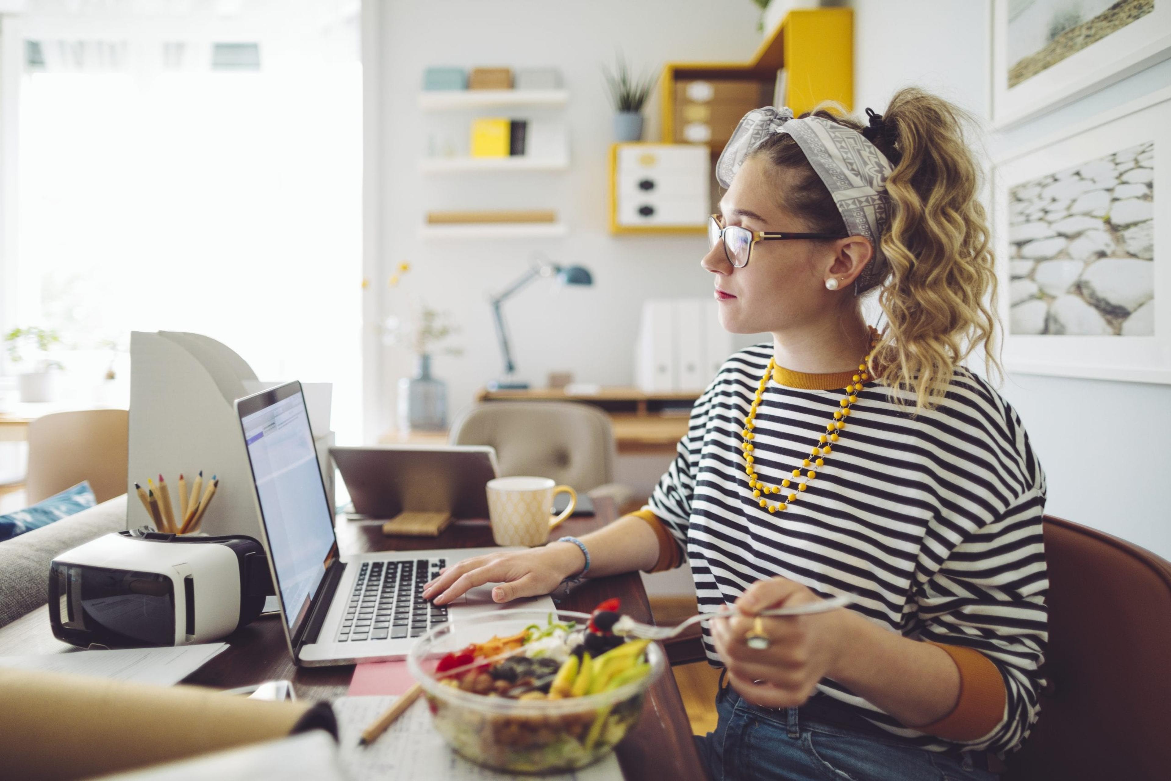 Woman eating a salad working from home