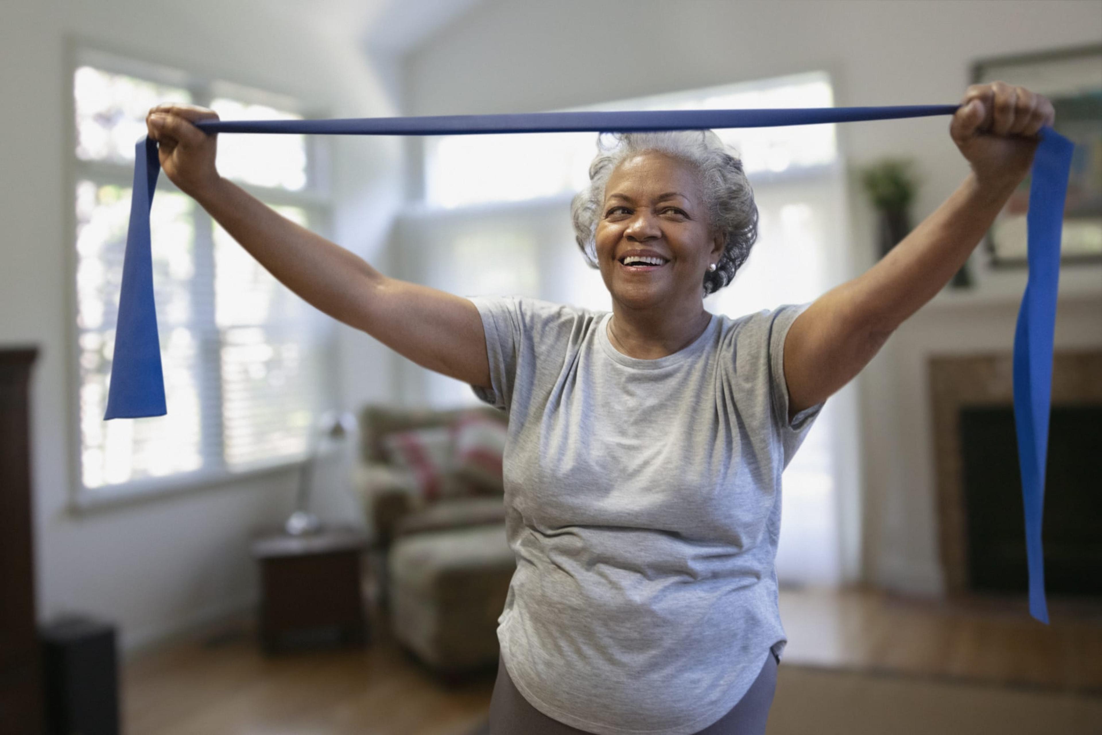 Senior Black woman stretches in her home