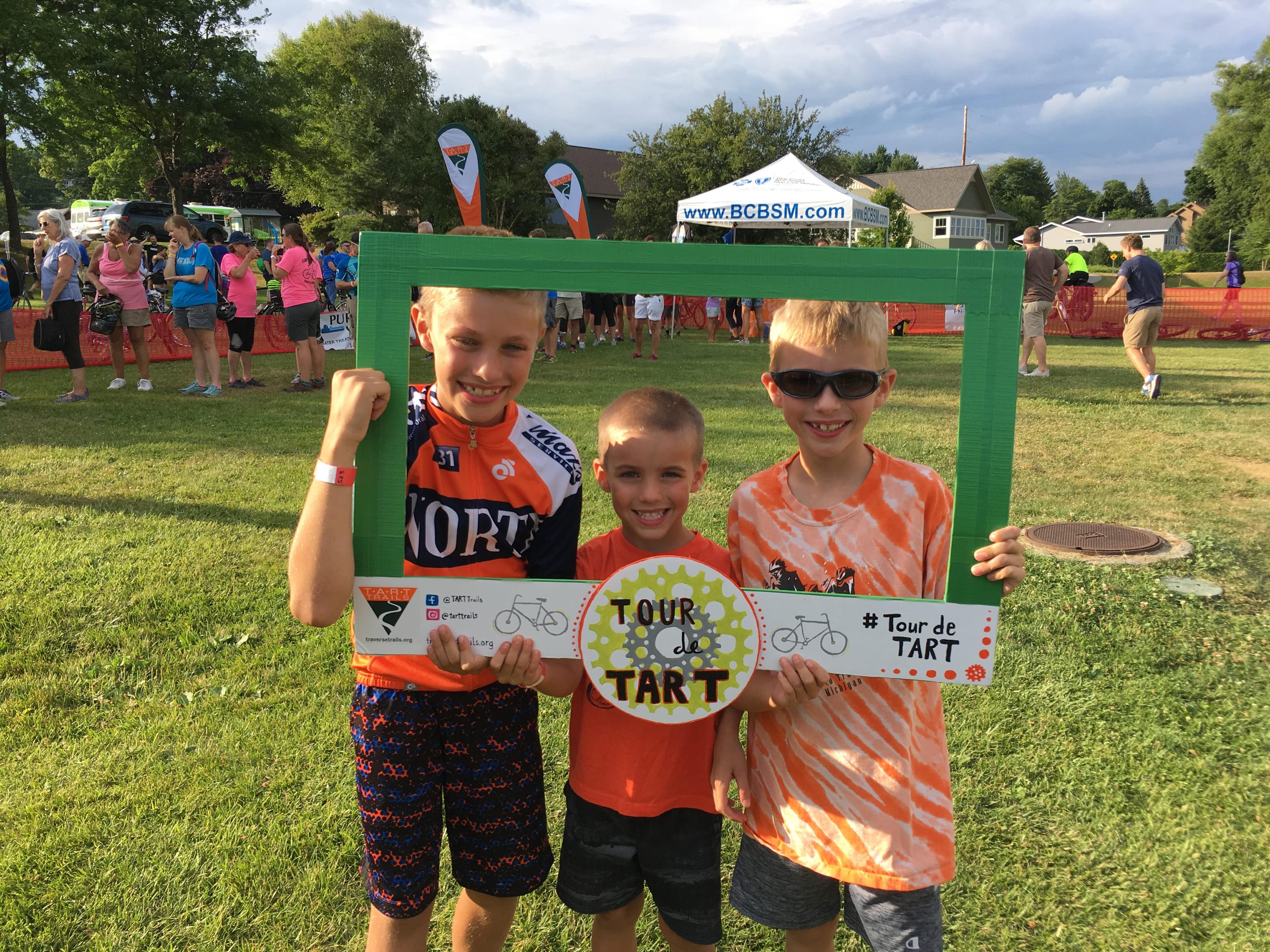 Three boys hold a Tour de TART frame as they pose for a picture.