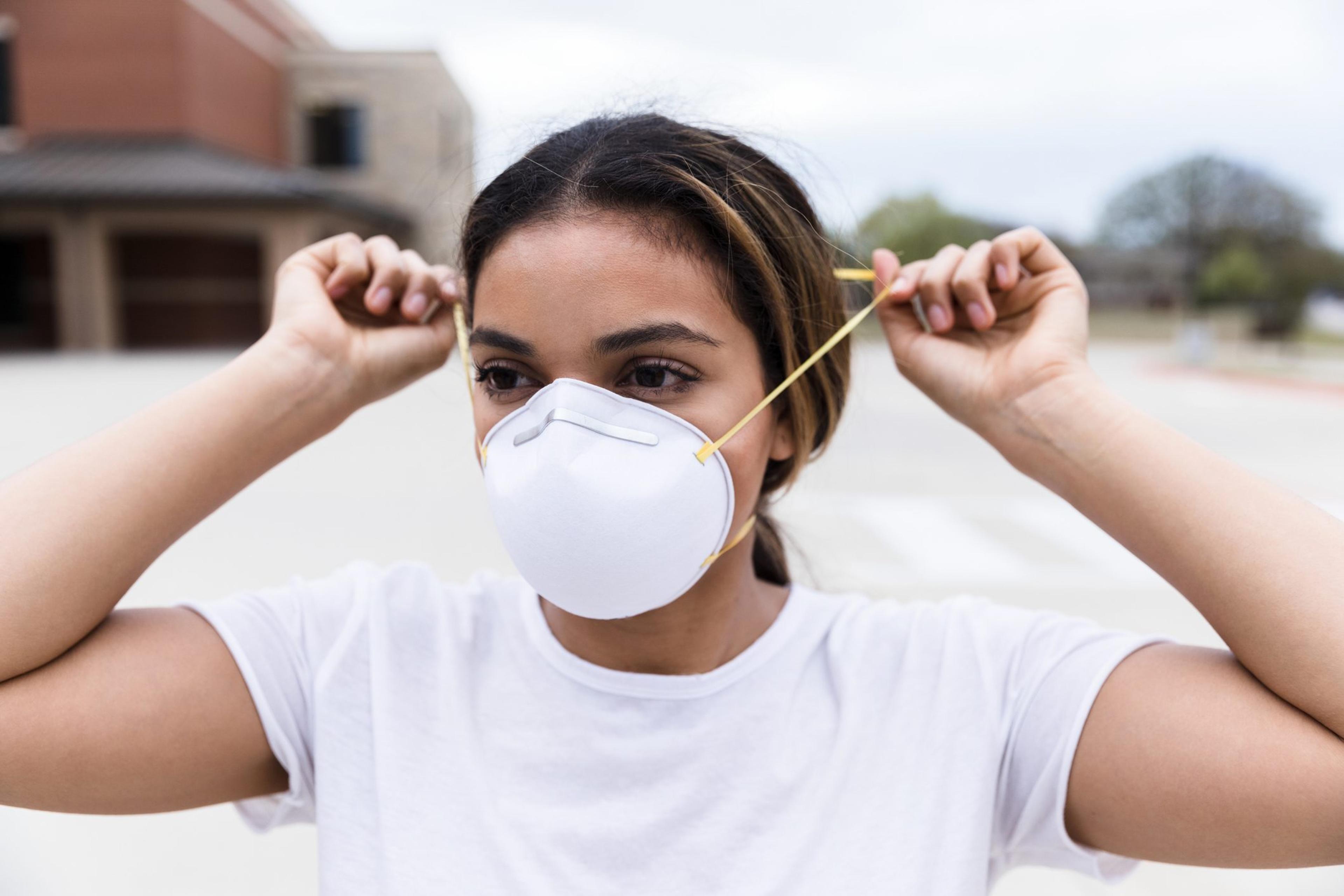 Woman puts on a N95 mask outside