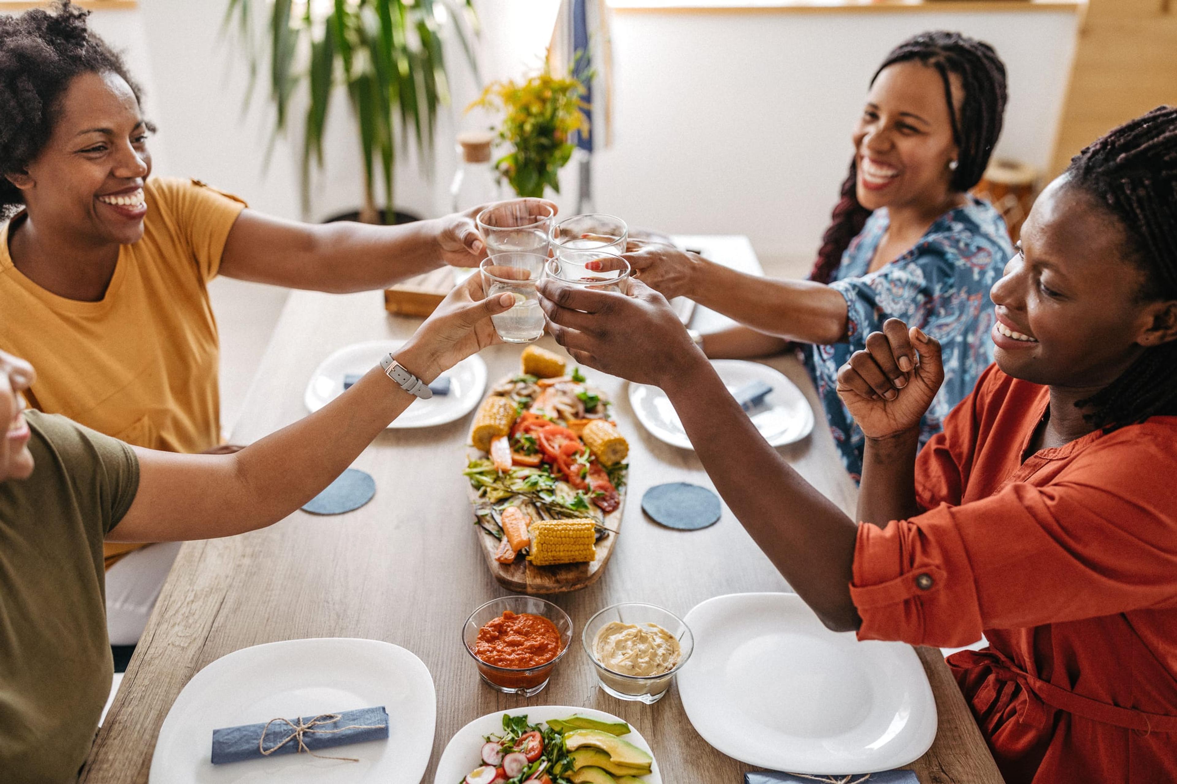 Woman cheers their glasses over a meal