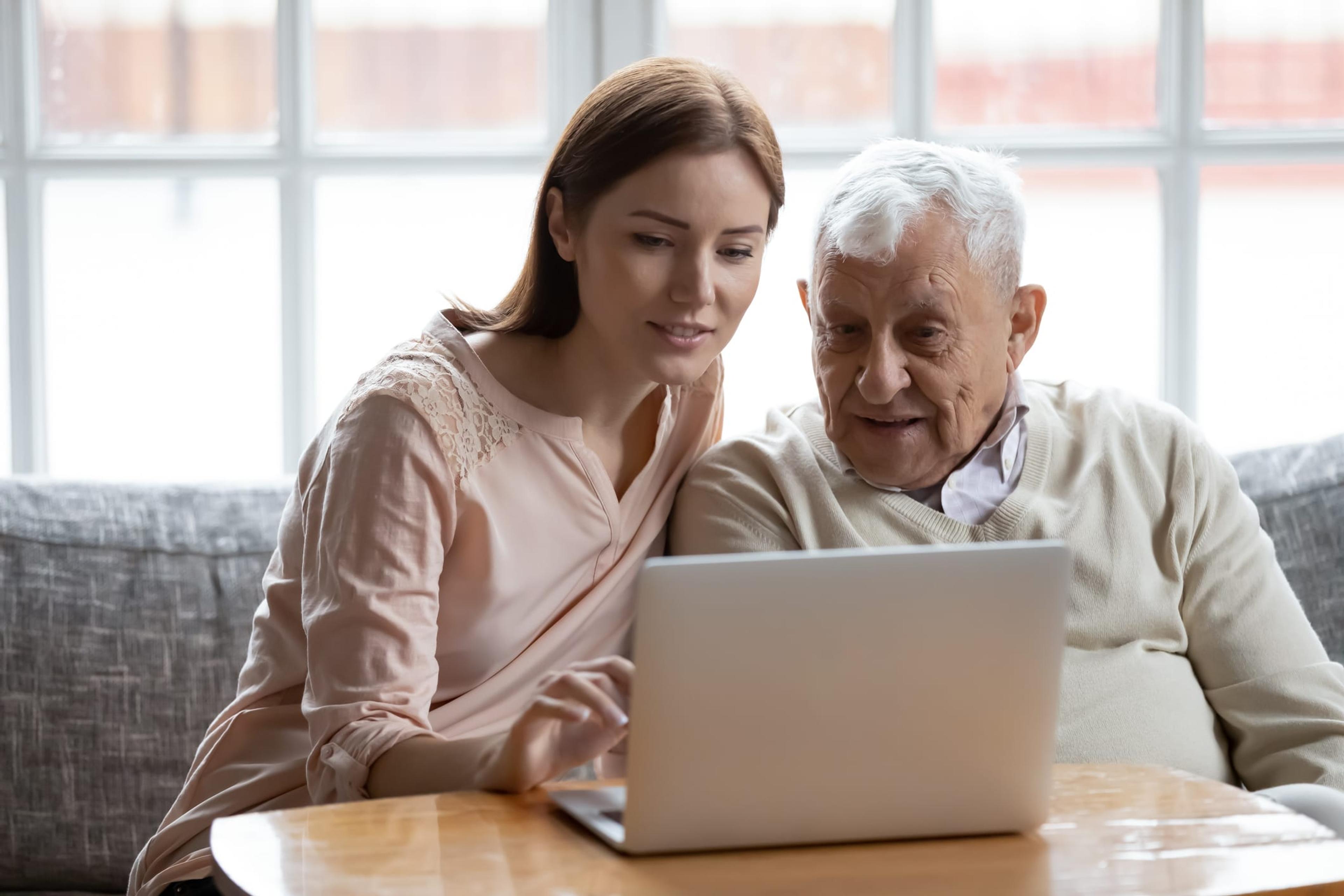 Woman helps older man with a laptop computer