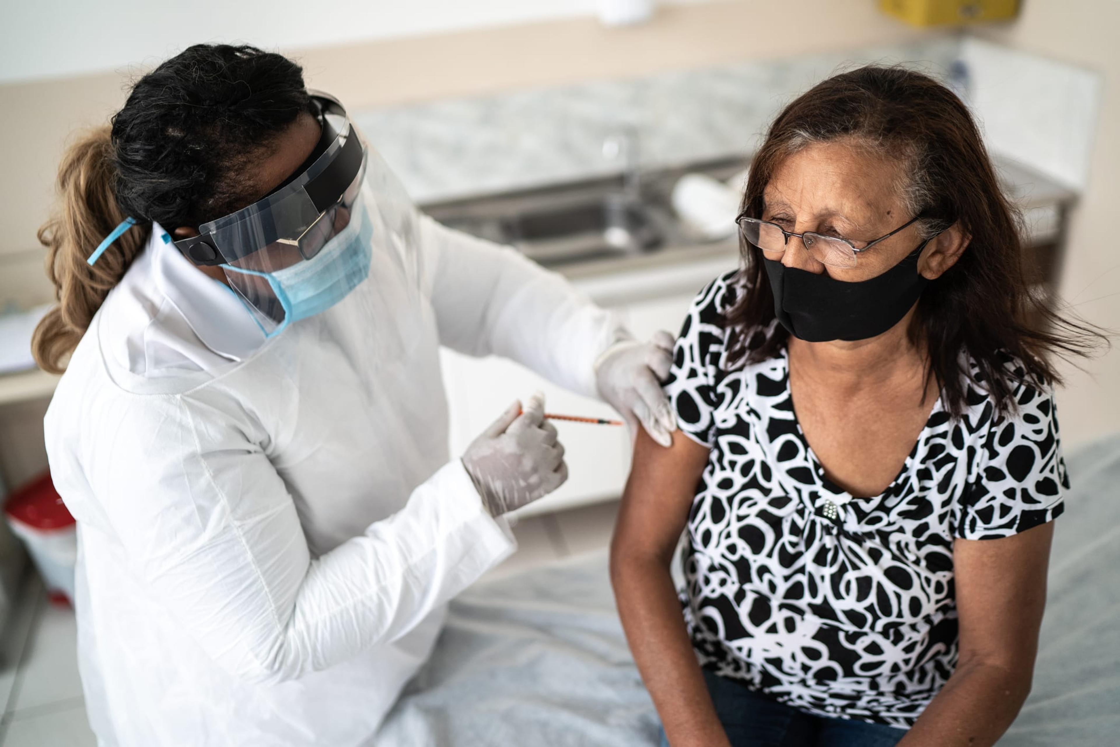 Senior woman being vaccinated wearing face mask