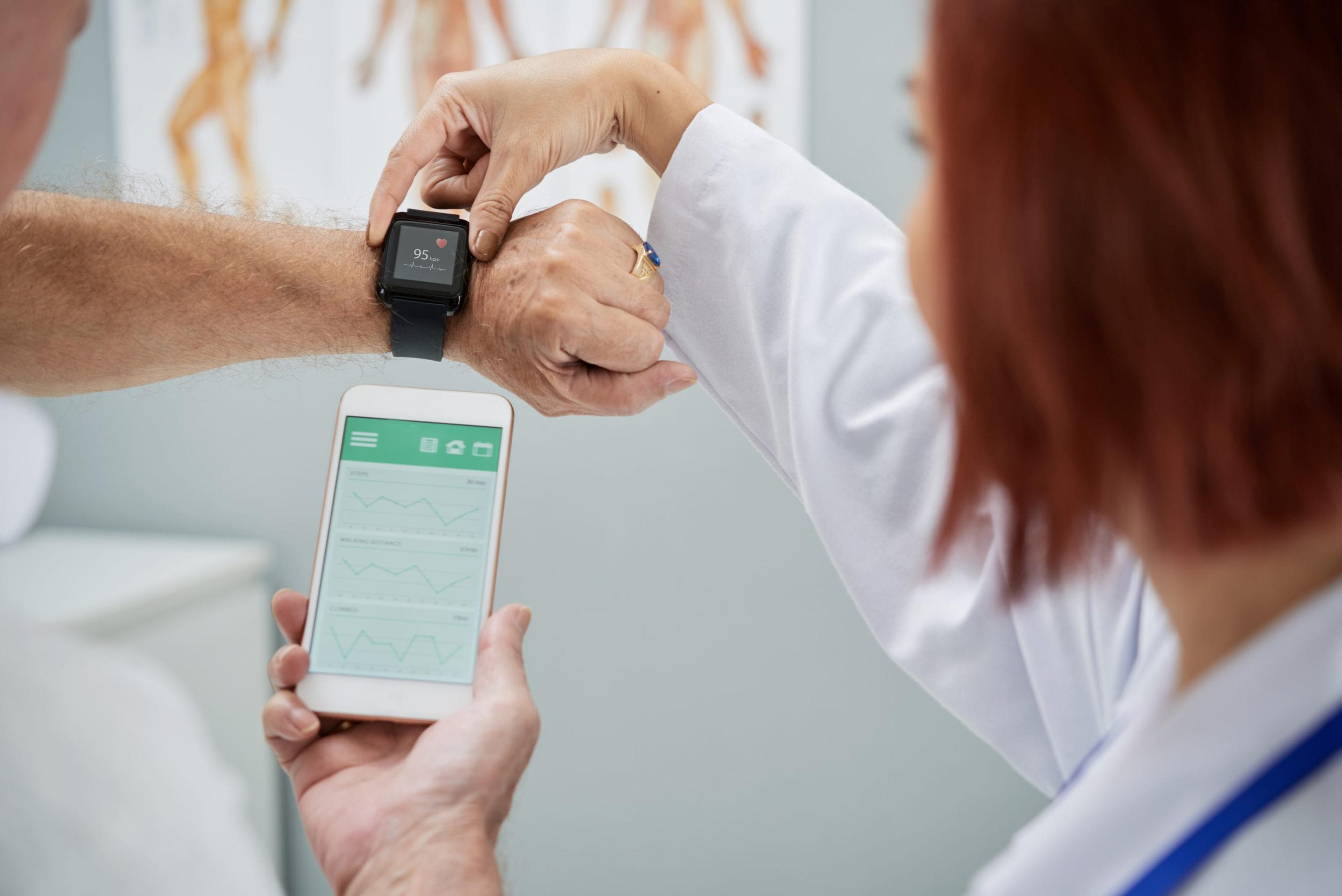 Doctor shows patient how a watch connects with an app on phone.
