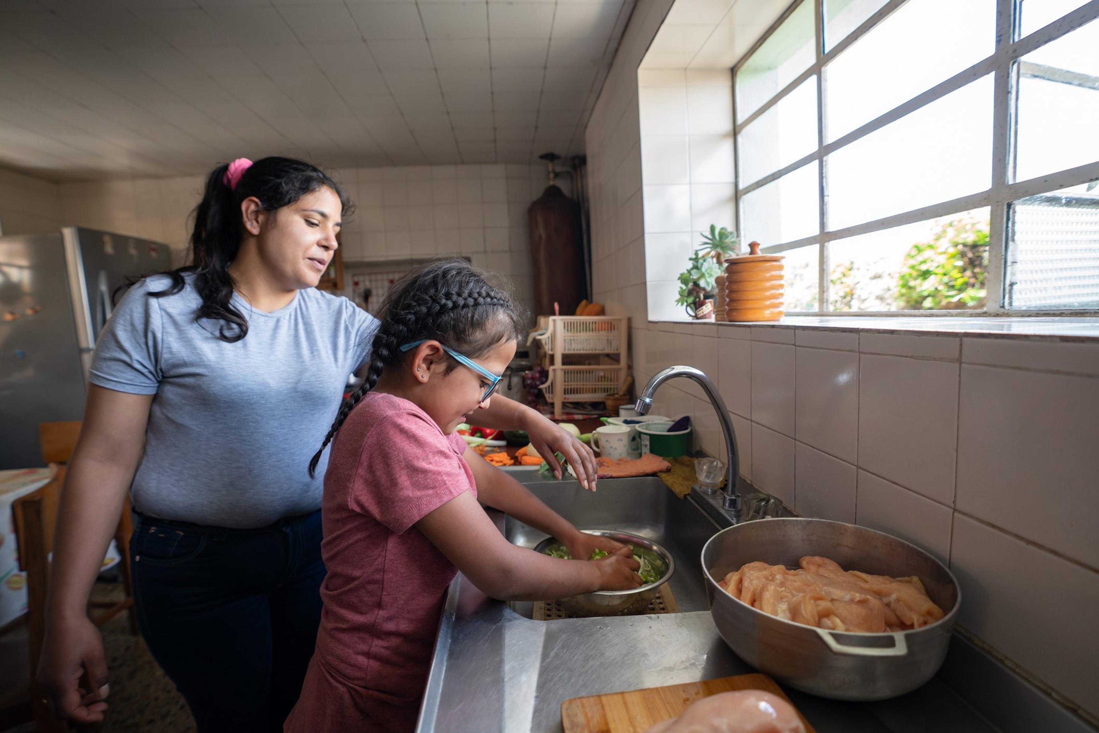 Latin American mother teaching her daughter to cook