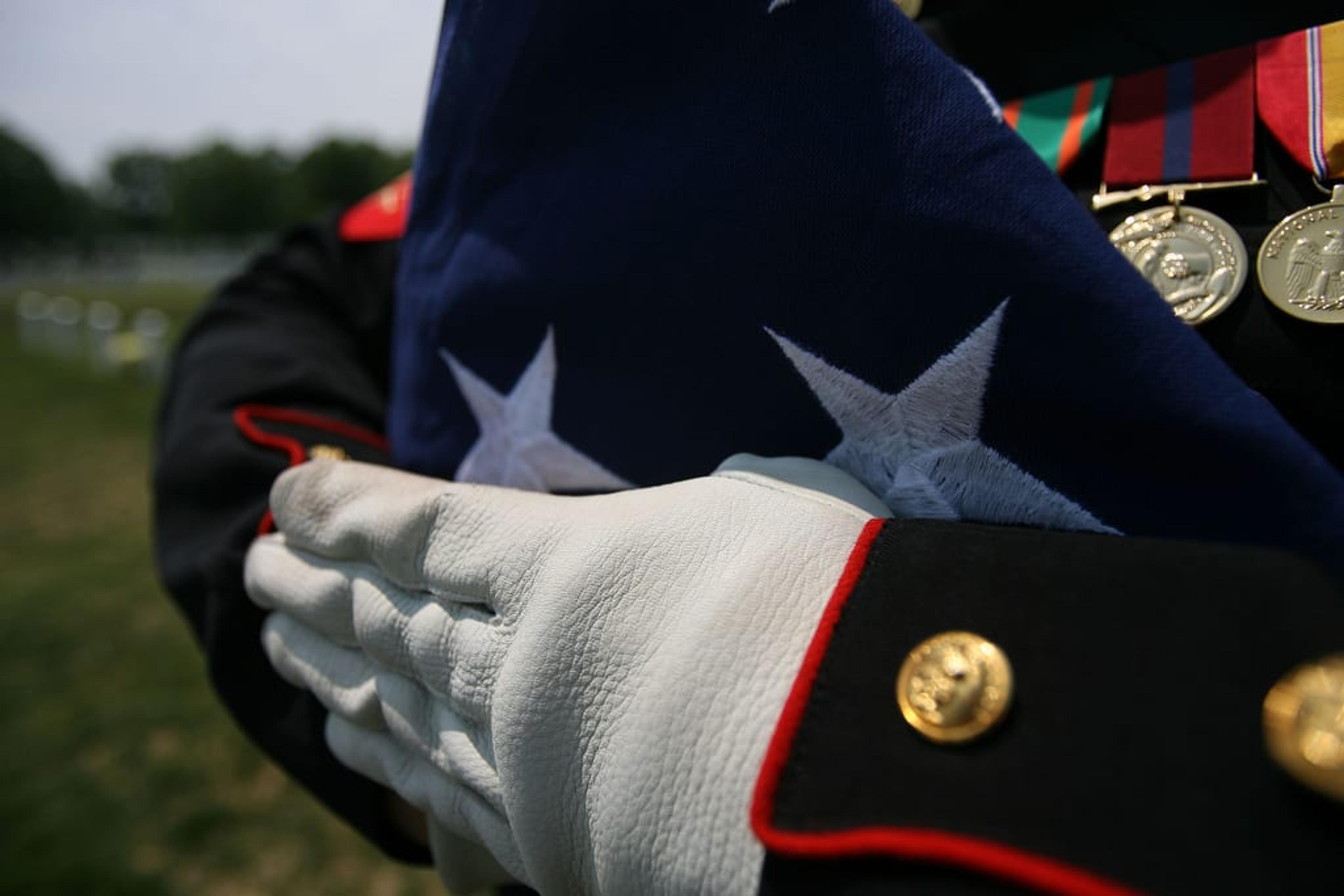 Solider in uniform holding a folded flag