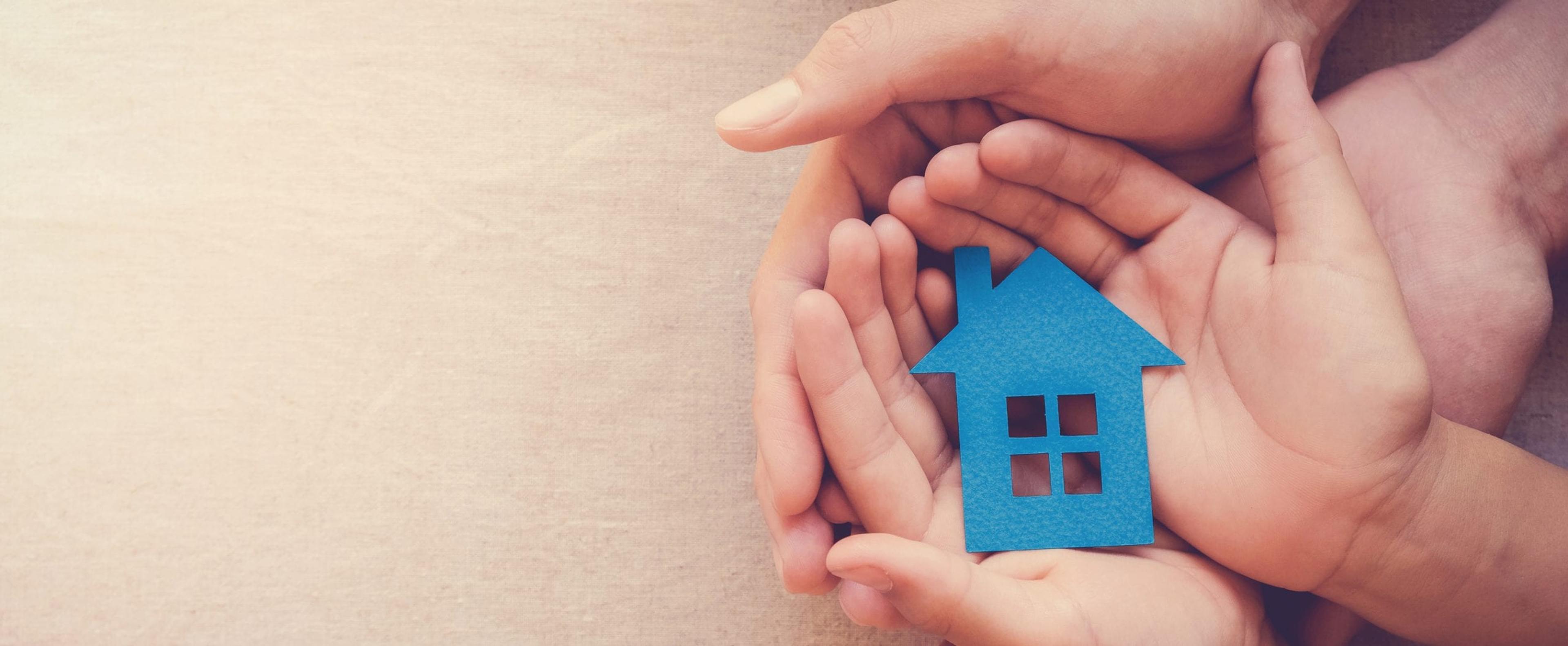 Hands holding a paper house