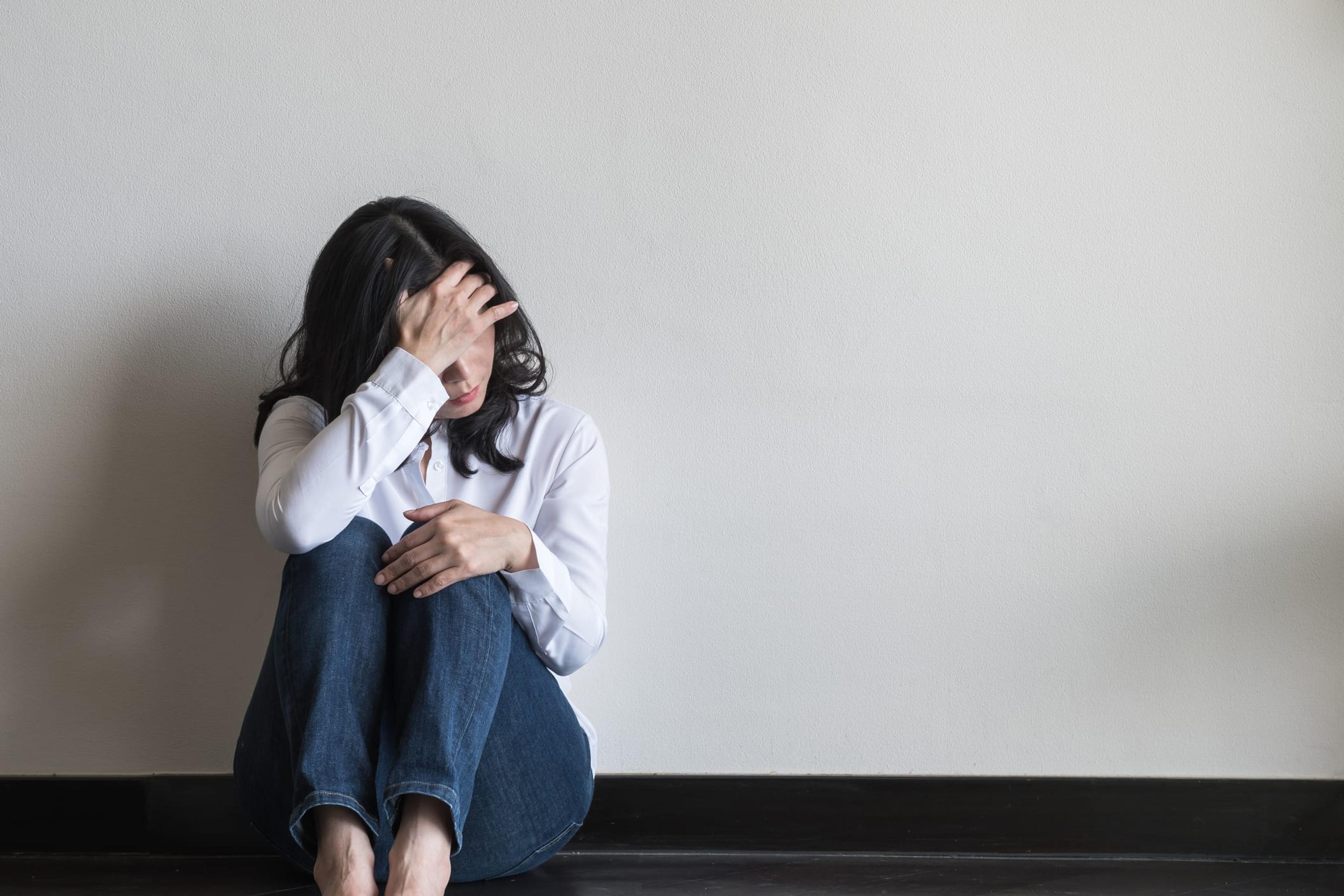 Woman sitting on the floor with her head in her hand
