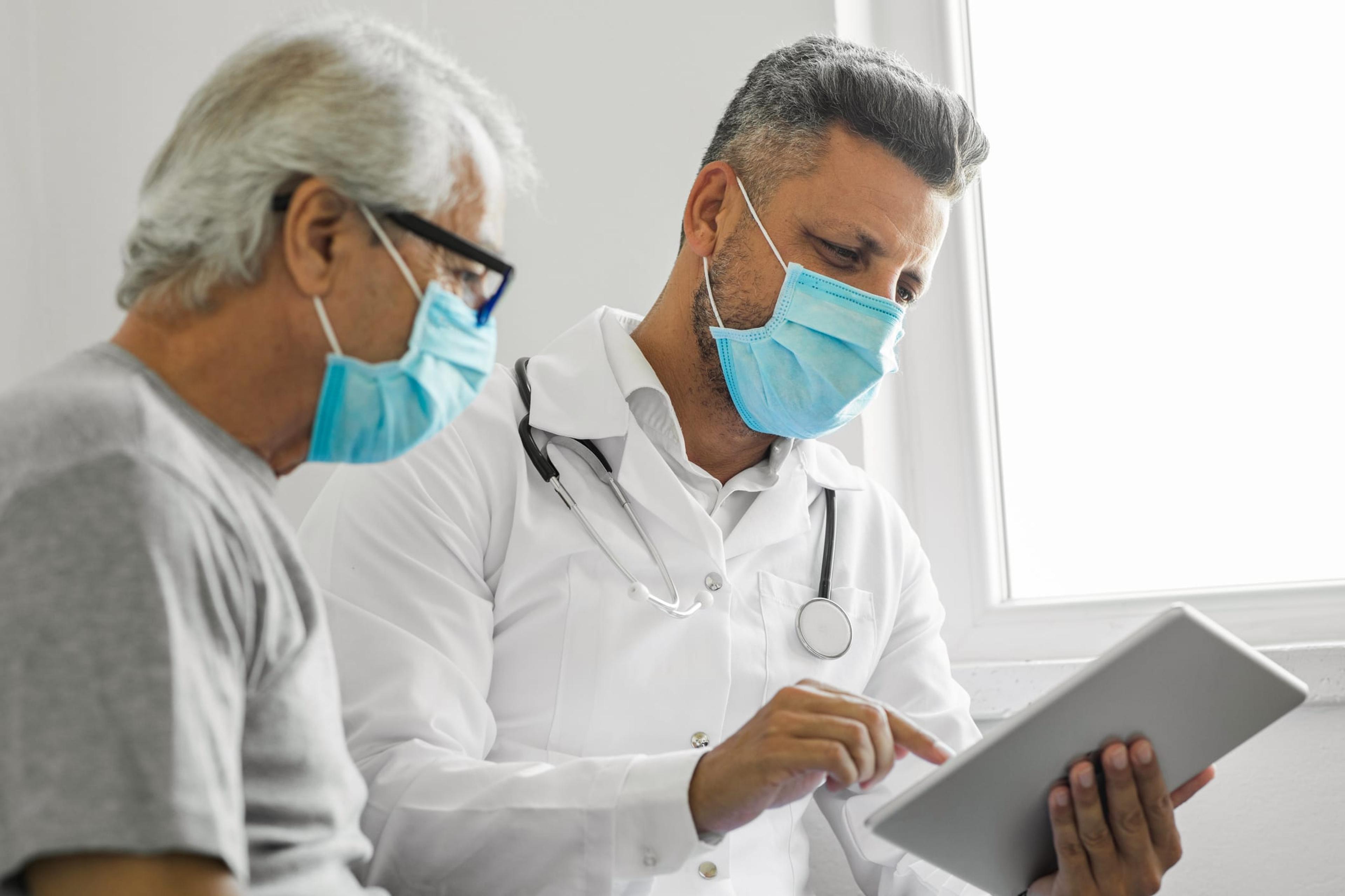 Doctor using digital tablet and talking to patient