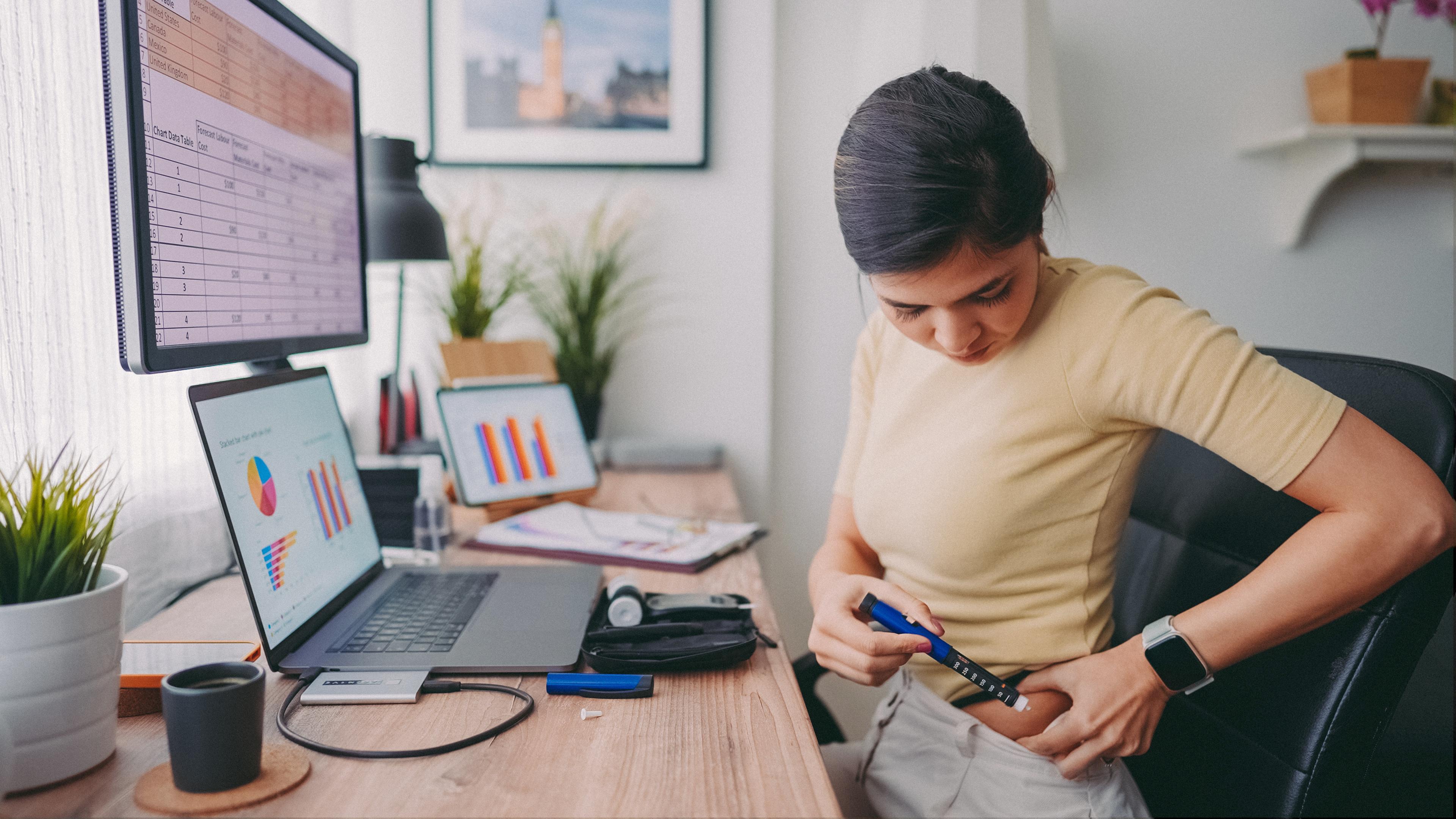 A woman administers insulin to her hip.