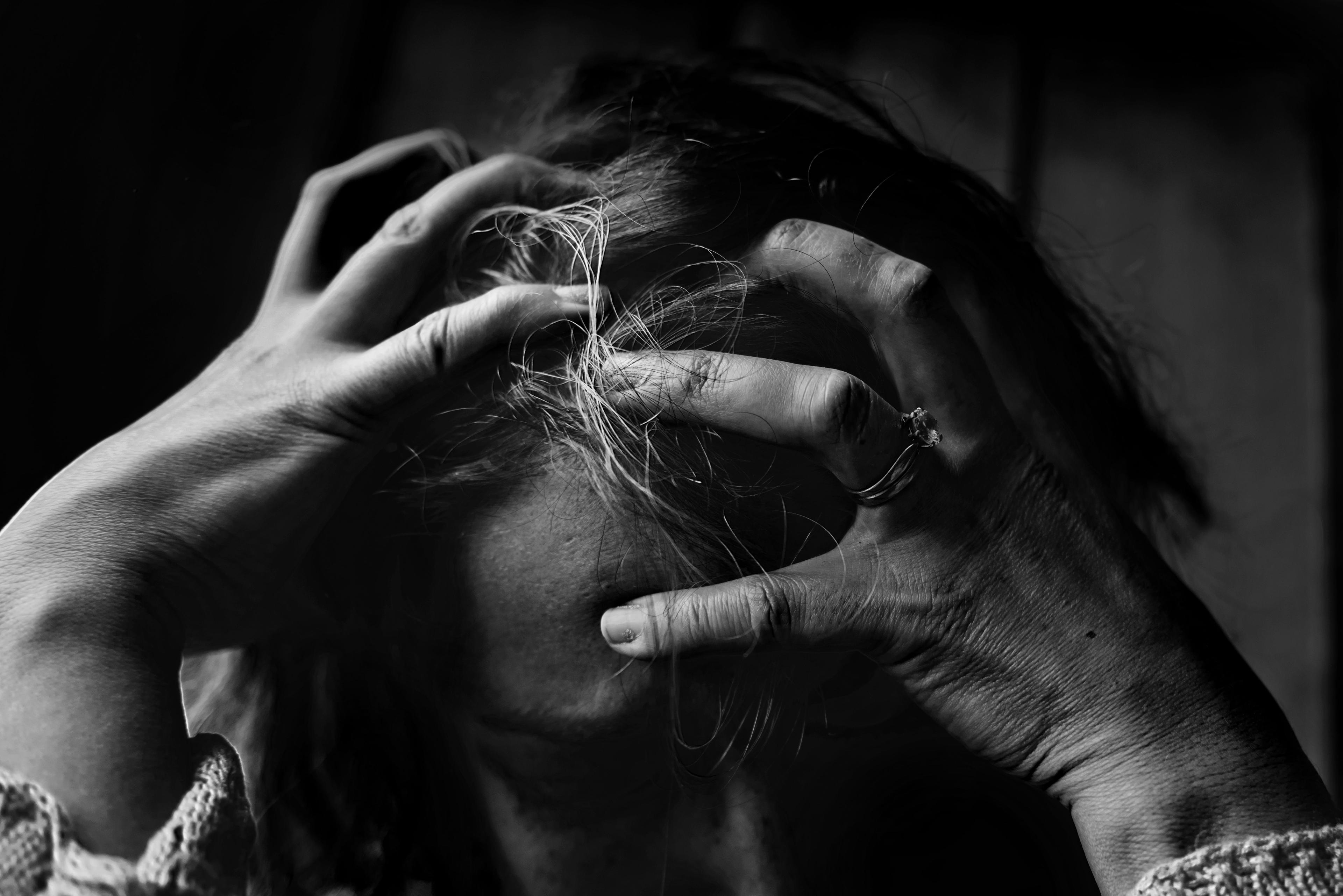 closeup of a person with hands on their head.