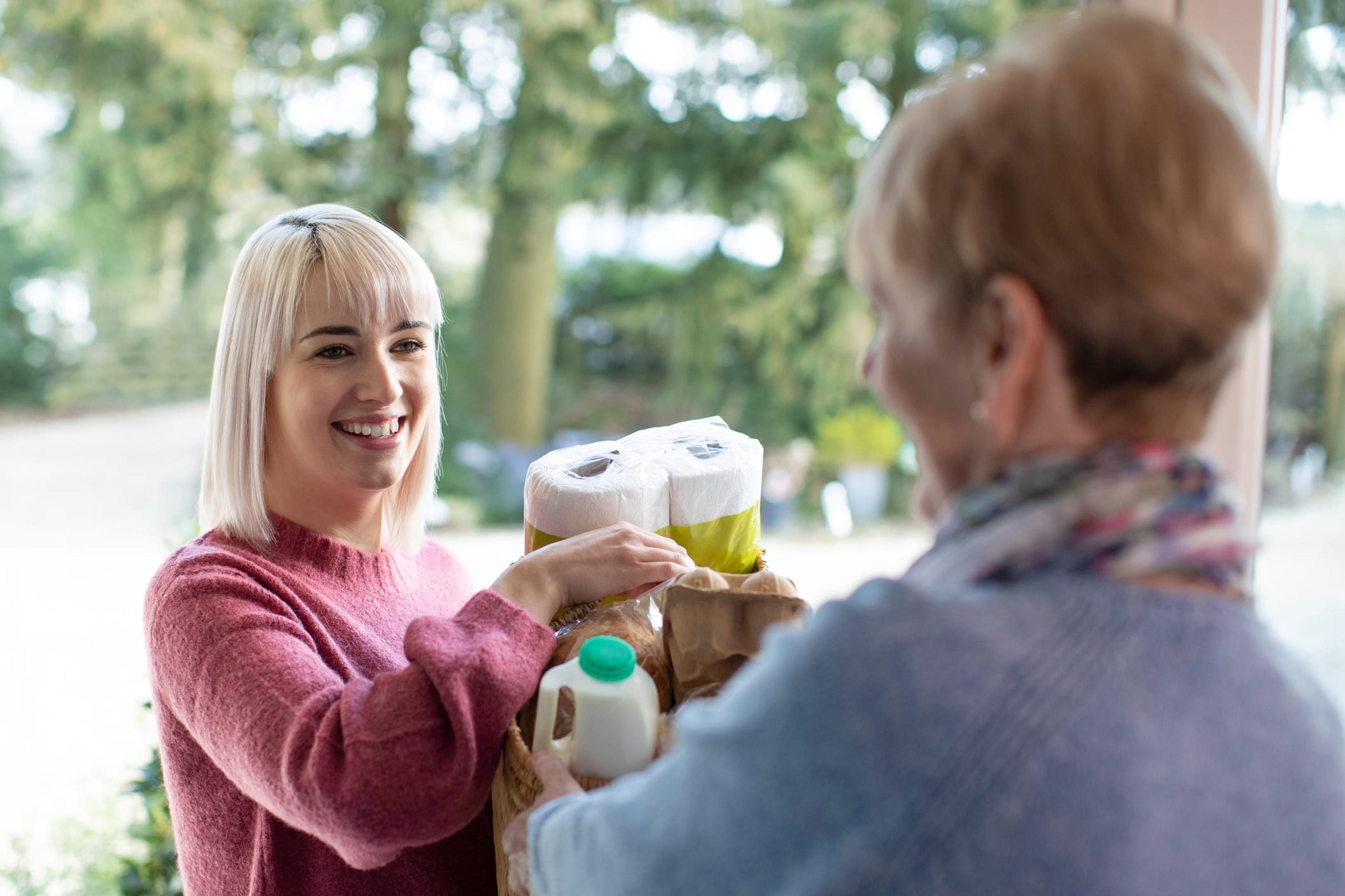 Young woman helping older woman with groceries