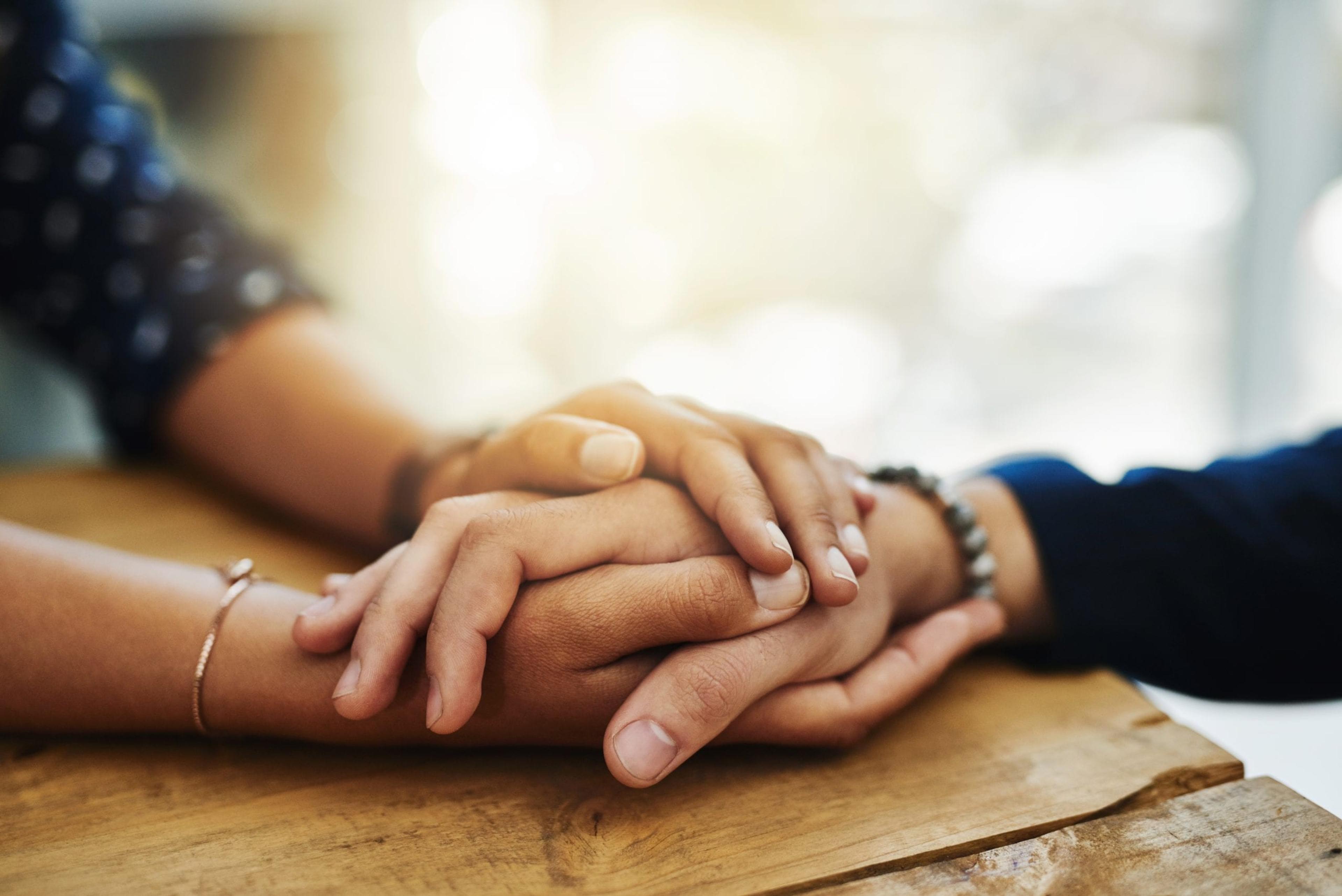 Image of two people holding hands in a closeup shot.
