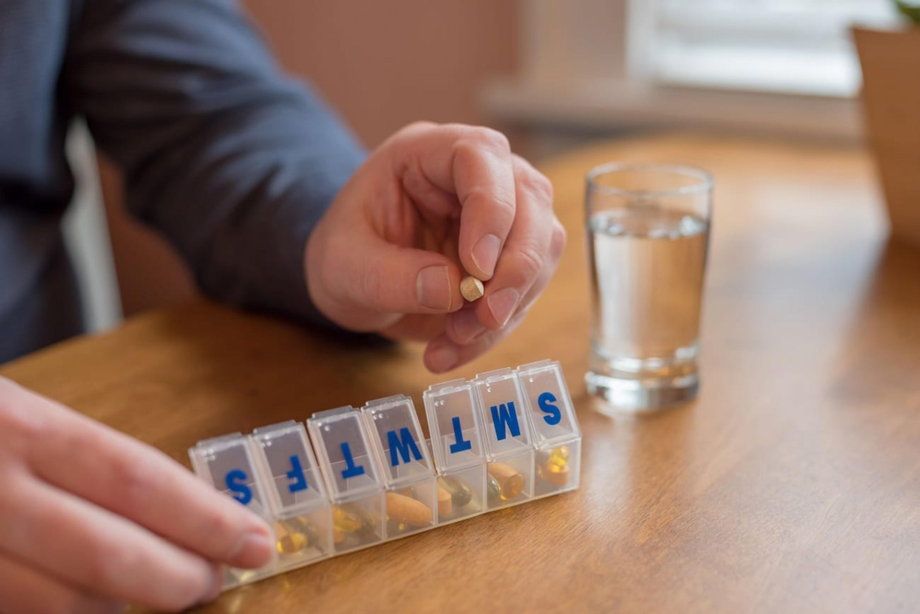 Man using a daily pill holder to take medication