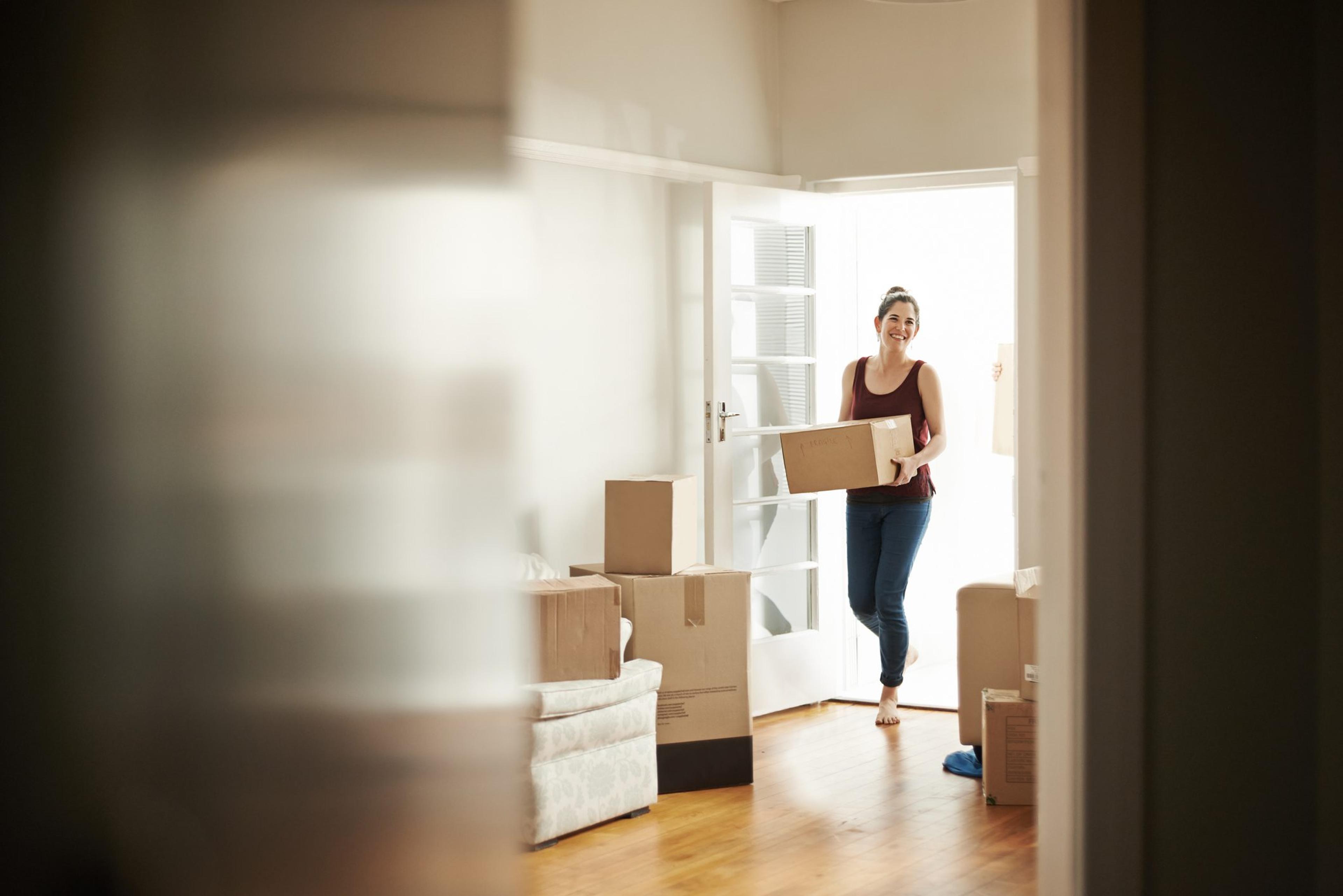 Woman carrying boxes while moving in to her new apartment in supportive housing to help her mental health