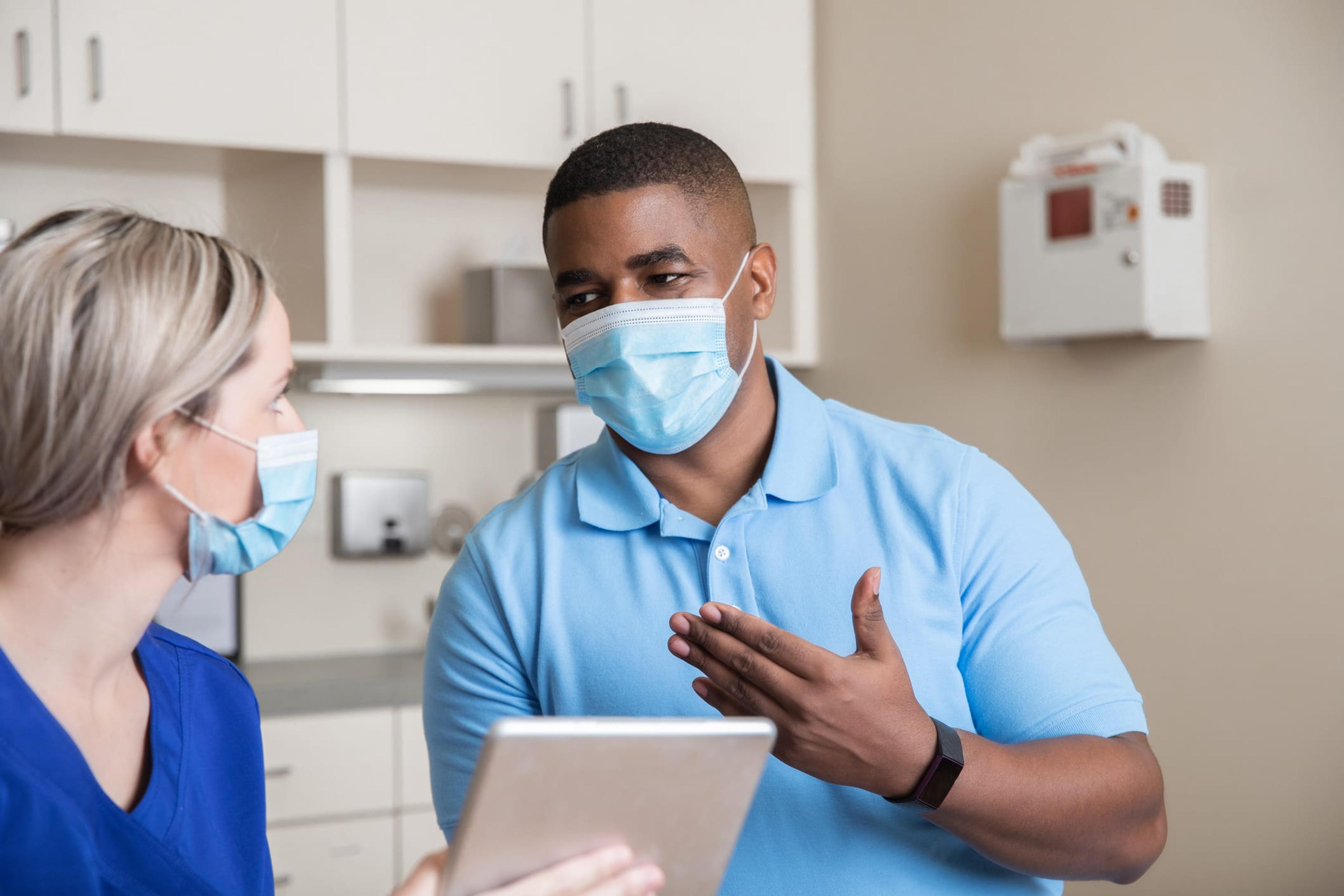 Adult man telling nurse his symptoms in exam room