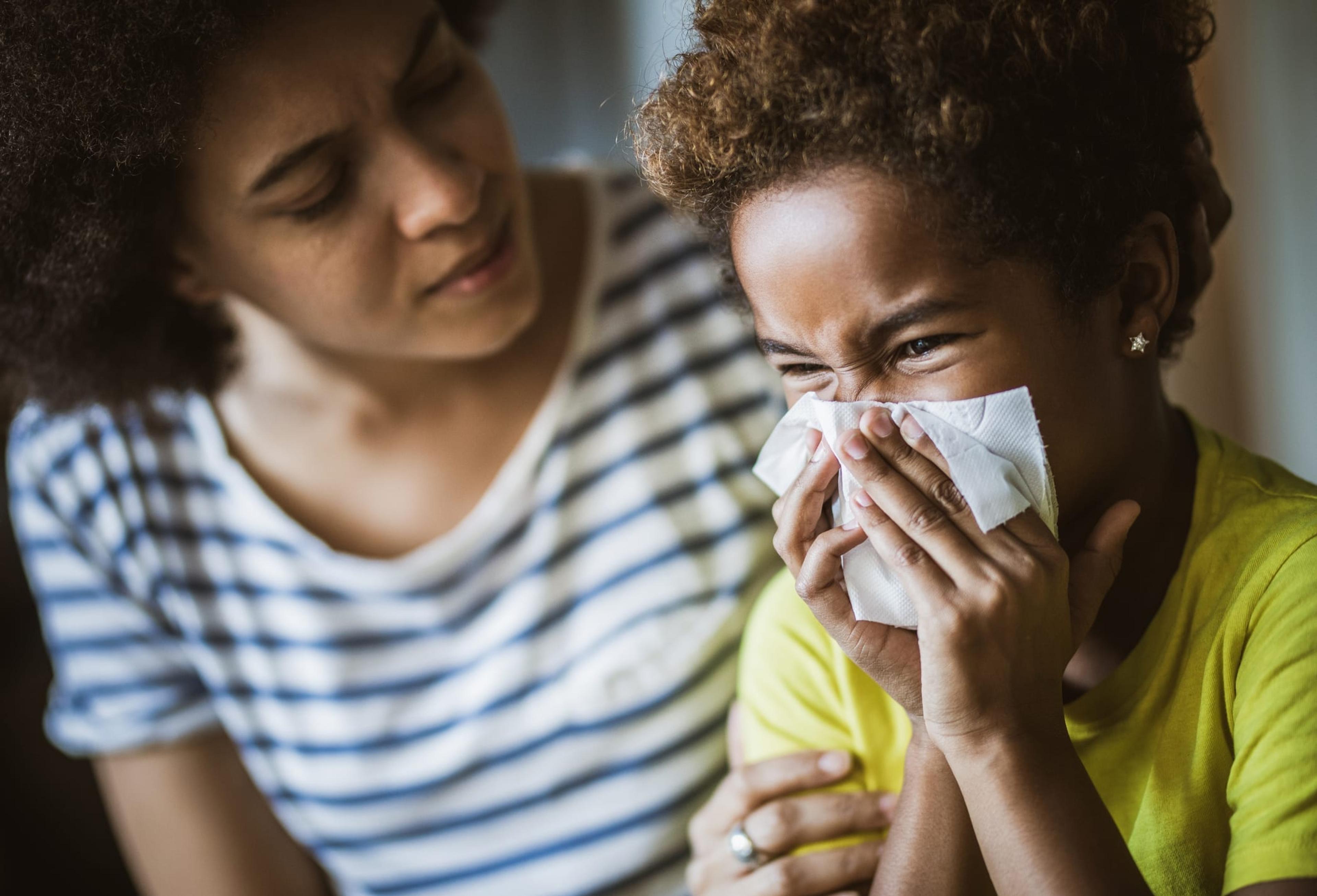 Woman helping her daughter blow her nose