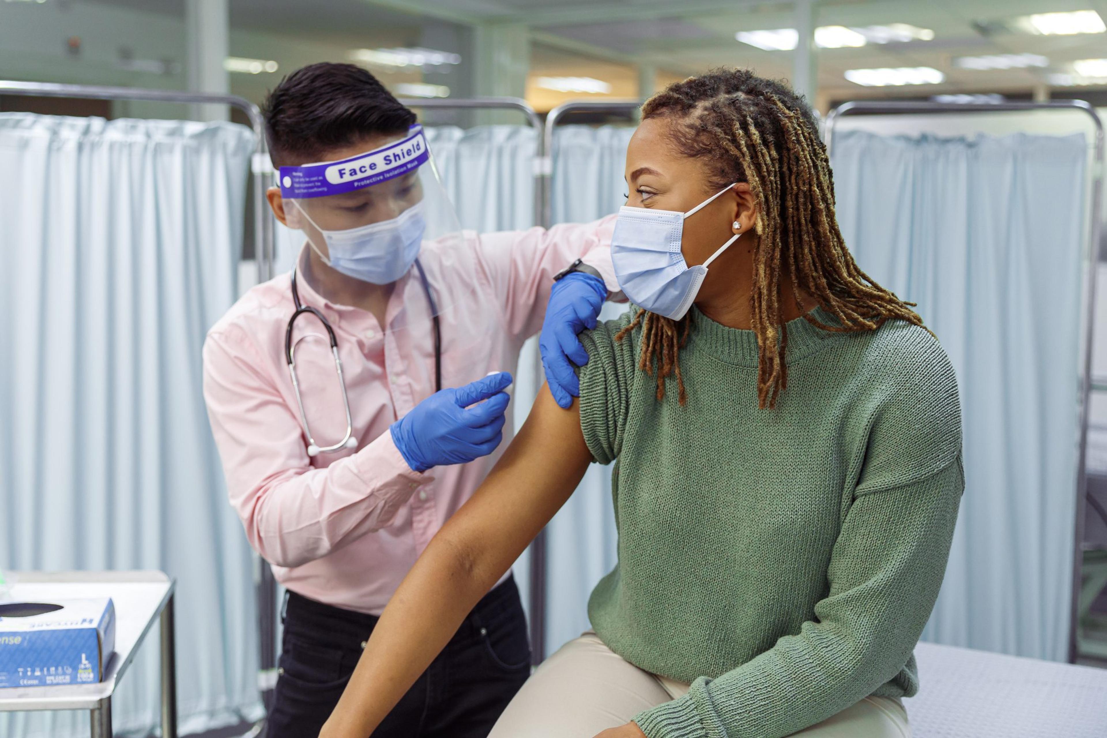 Woman receiving a vaccine while wearing a mask.