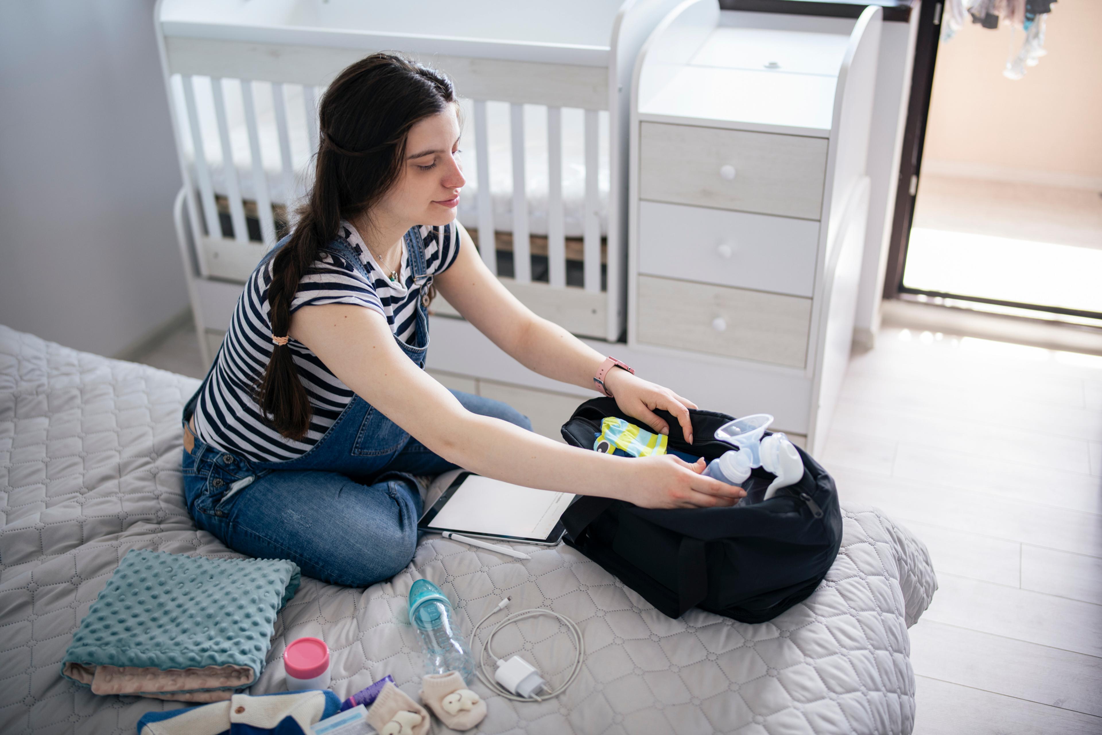 Pregnant woman preparing bag for the hospital for childbirth.