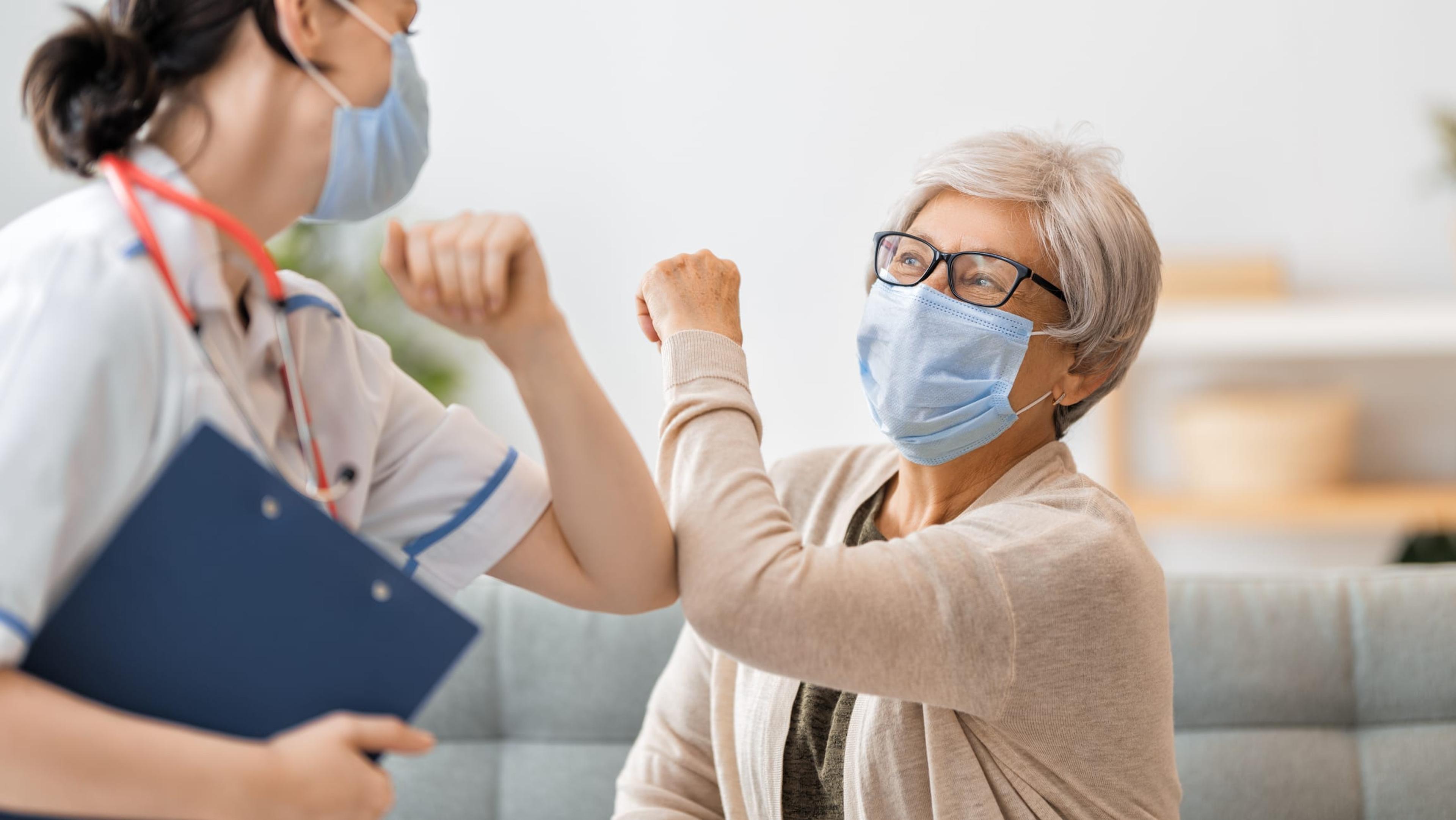 Woman and medical provider in masks bump elbows