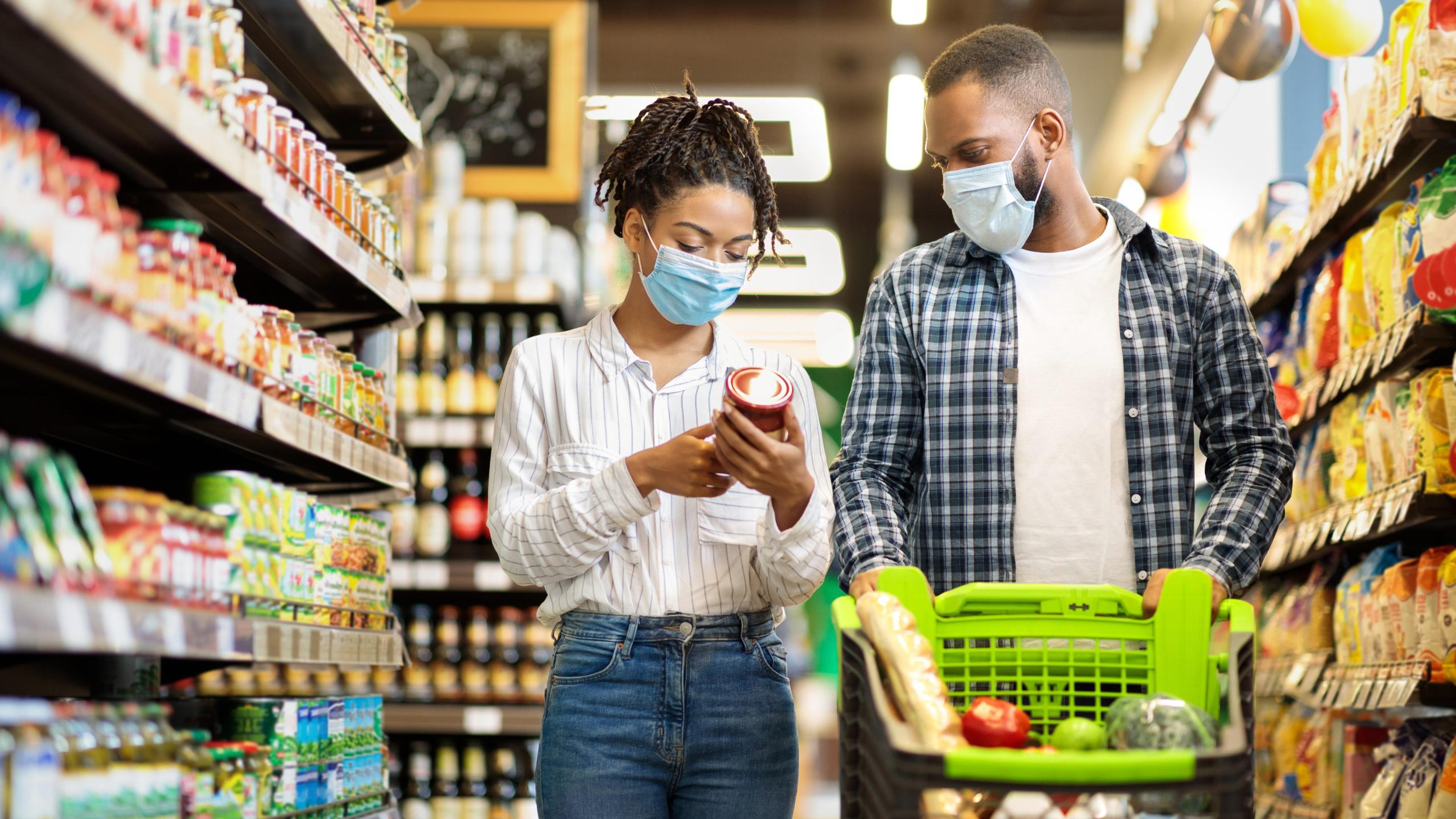 African Family Couple In Shop Buying Groceries Wearing Face Mask Choosing Food Goods Walking With Shopping Cart In Supermarket Store