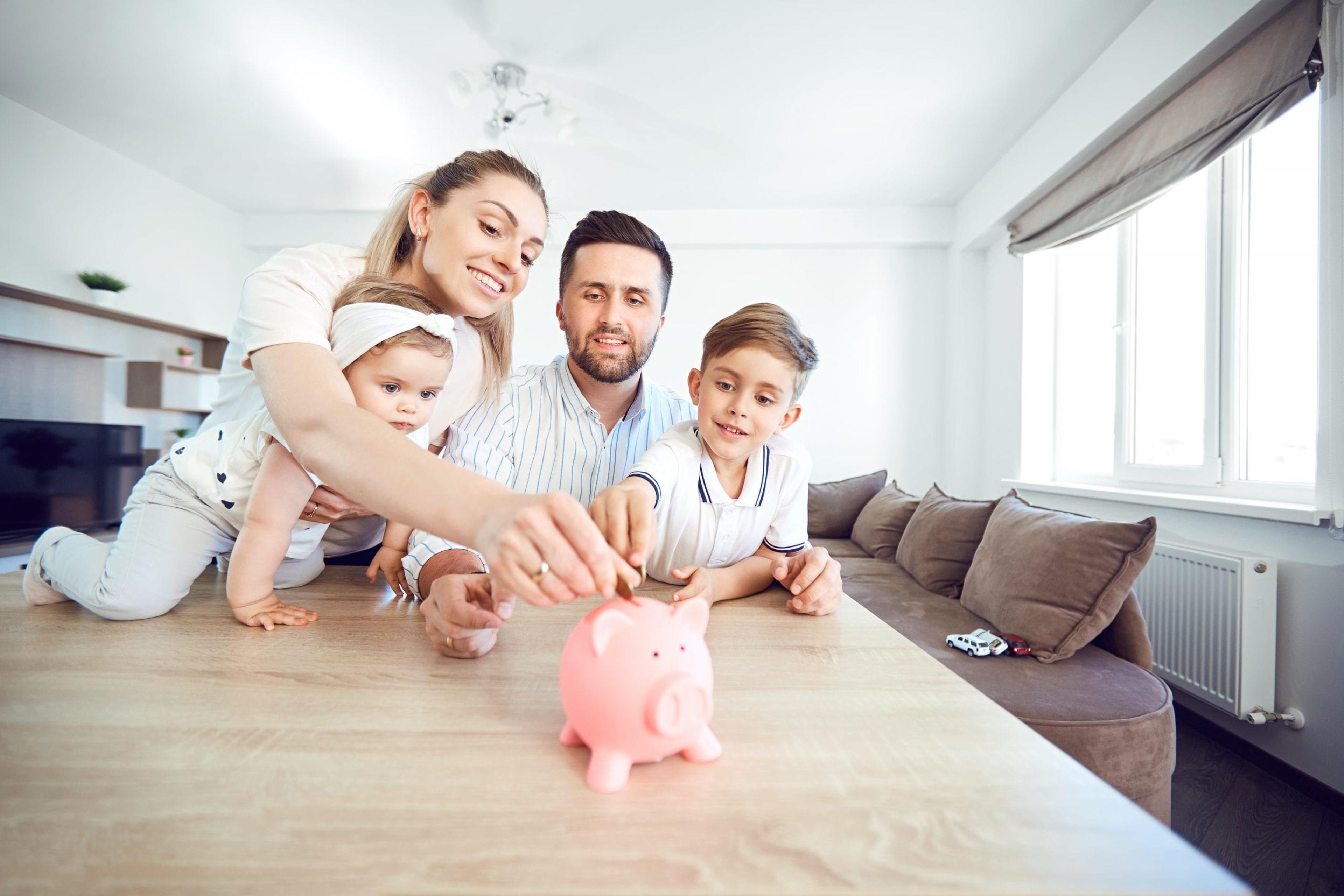 Young family putting money in a piggy bank.