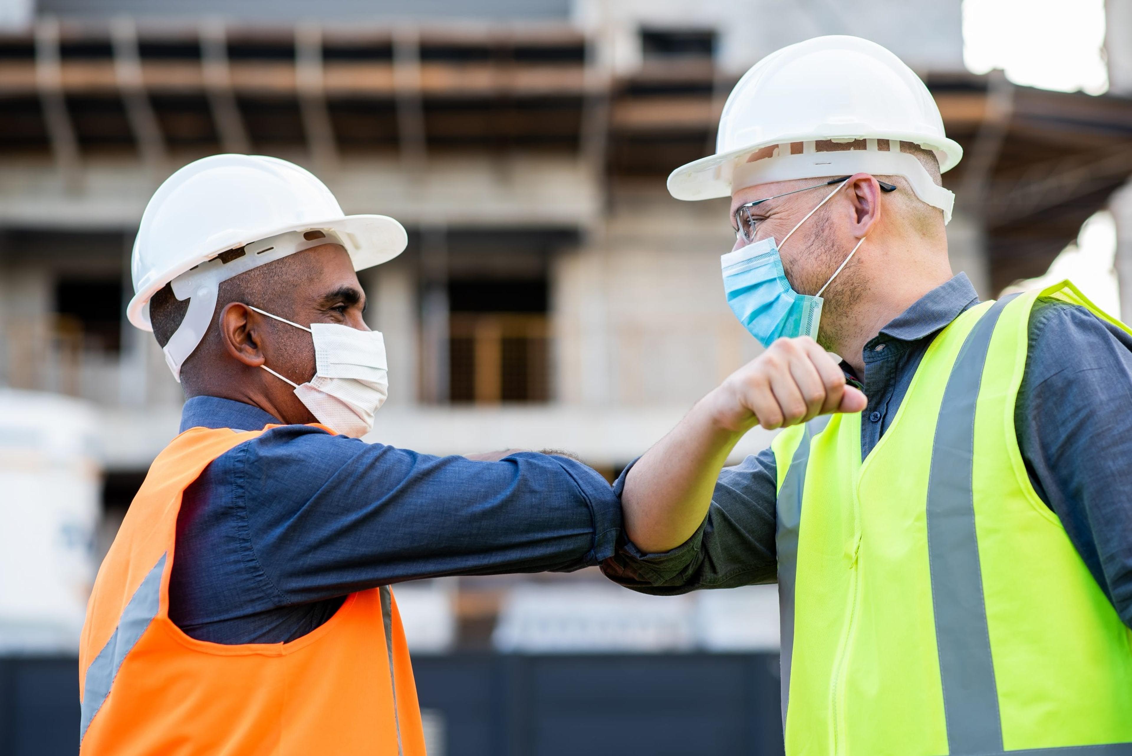 Workers in masks bumping elbows