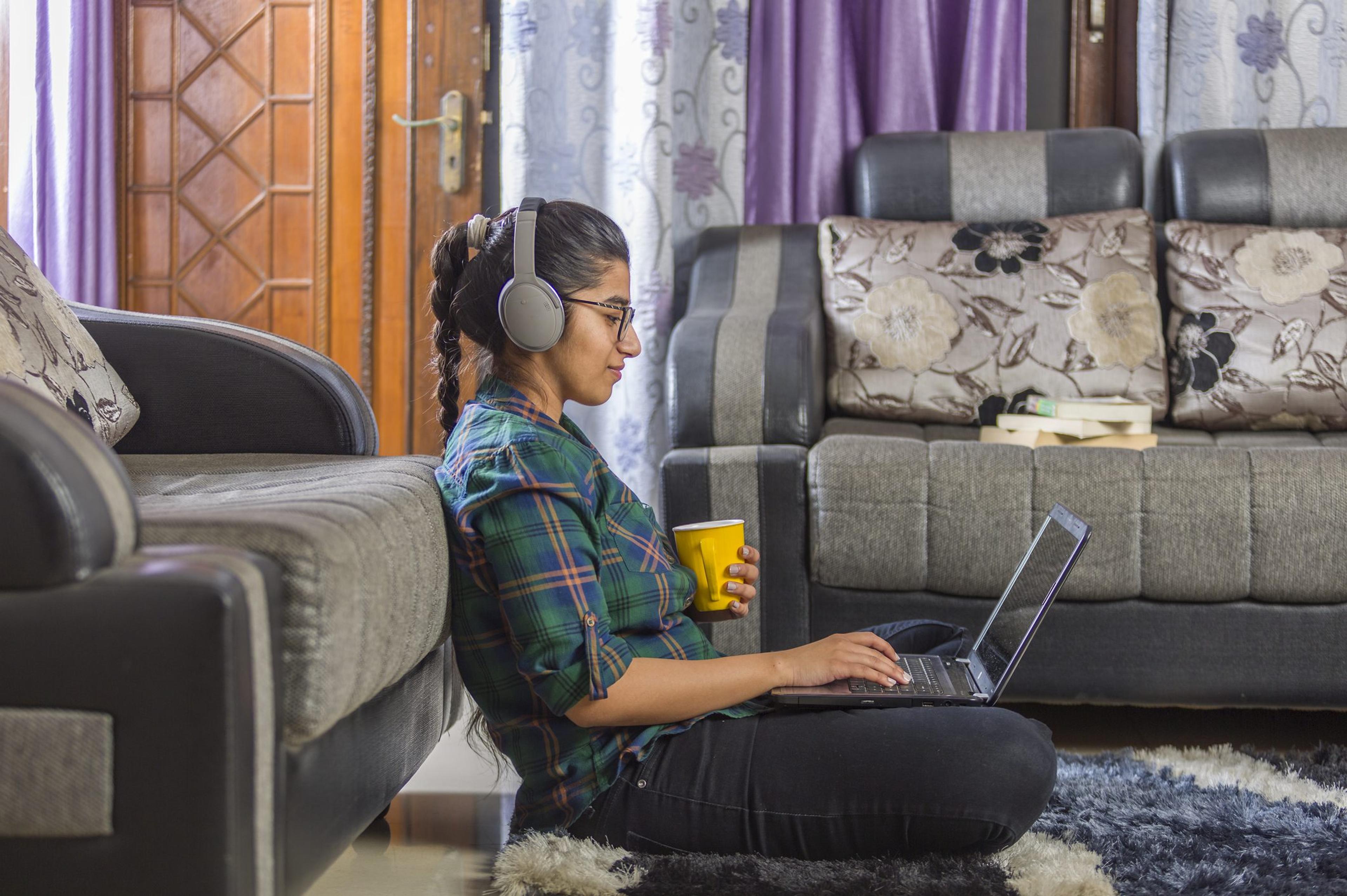 An Indian girl using laptop, sitting on floor