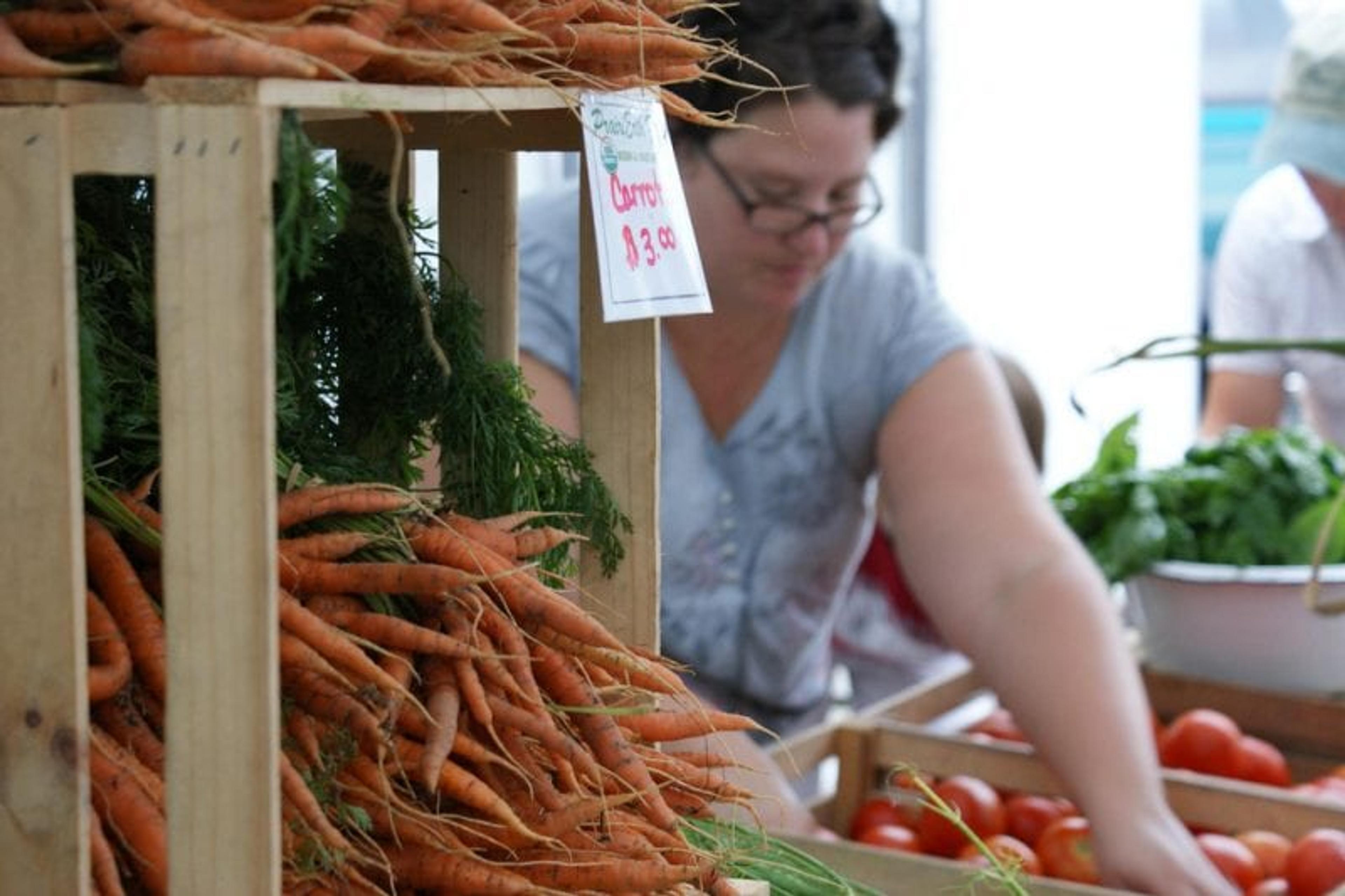 Image of a farmers market worker sorting various vegetables.