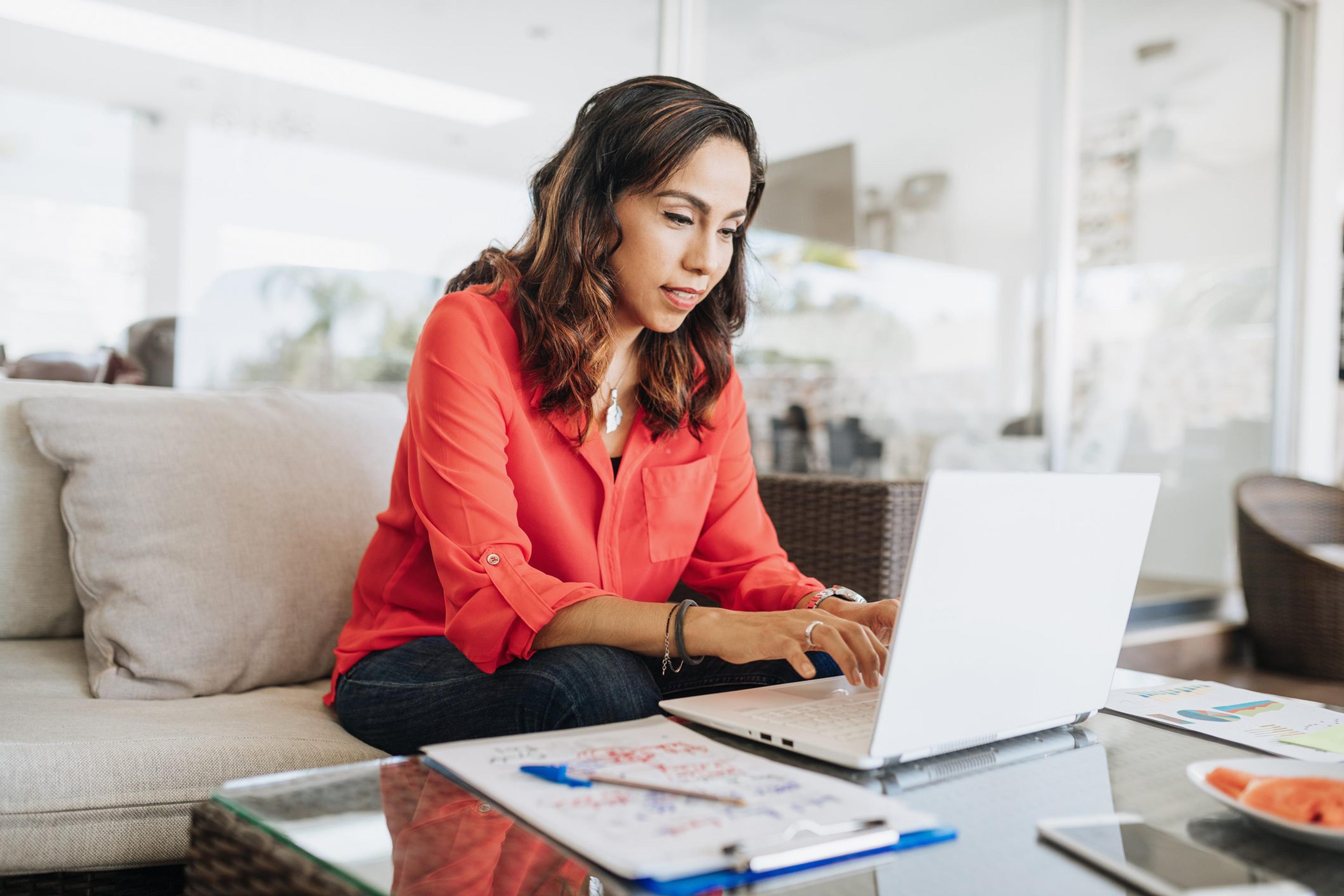 Woman views her laptop screen while sitting on her couch