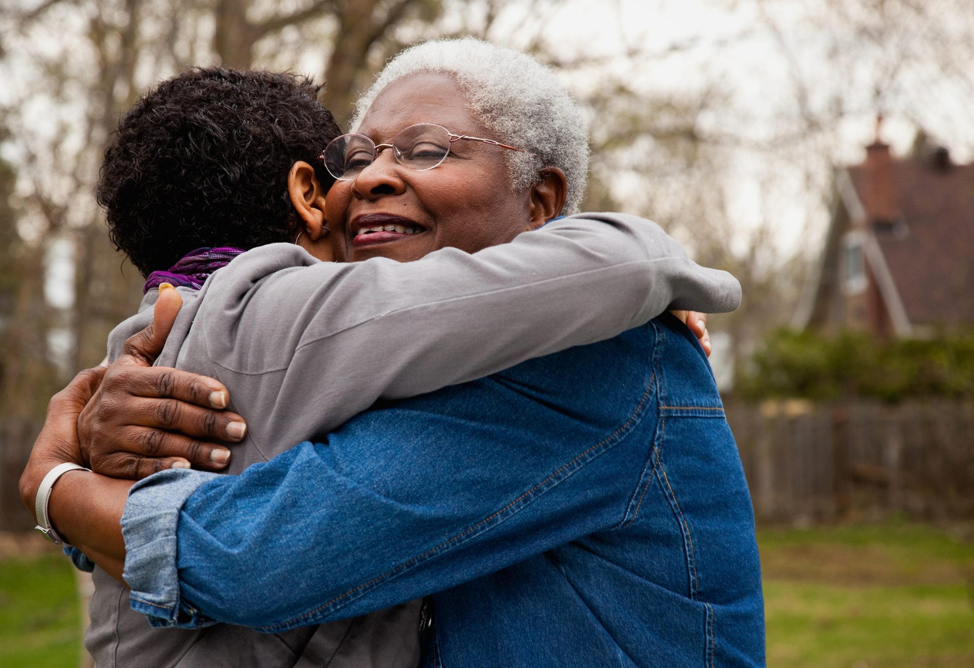 Senior woman hugging younger person