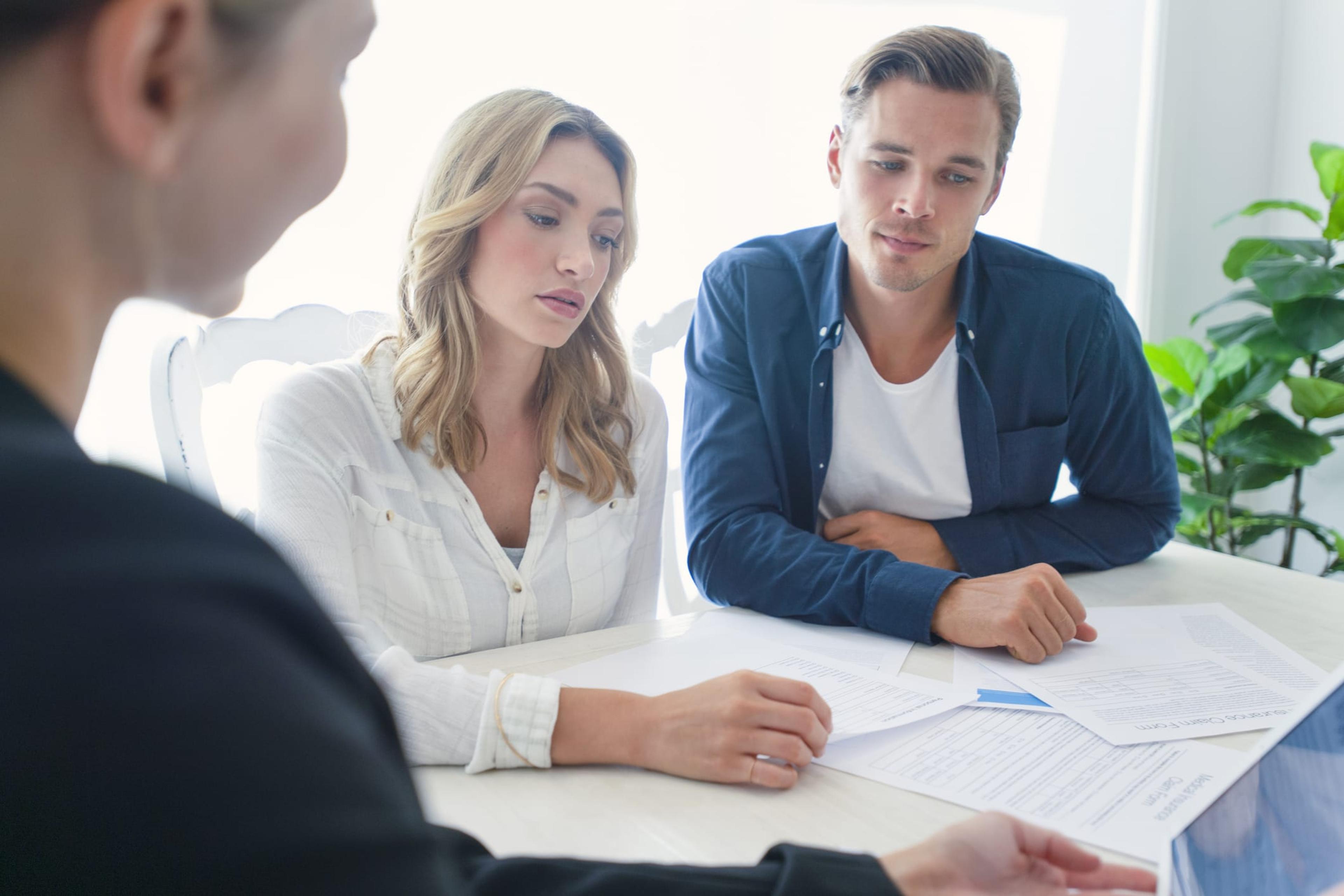 Insurance agent with couple looking through documents.