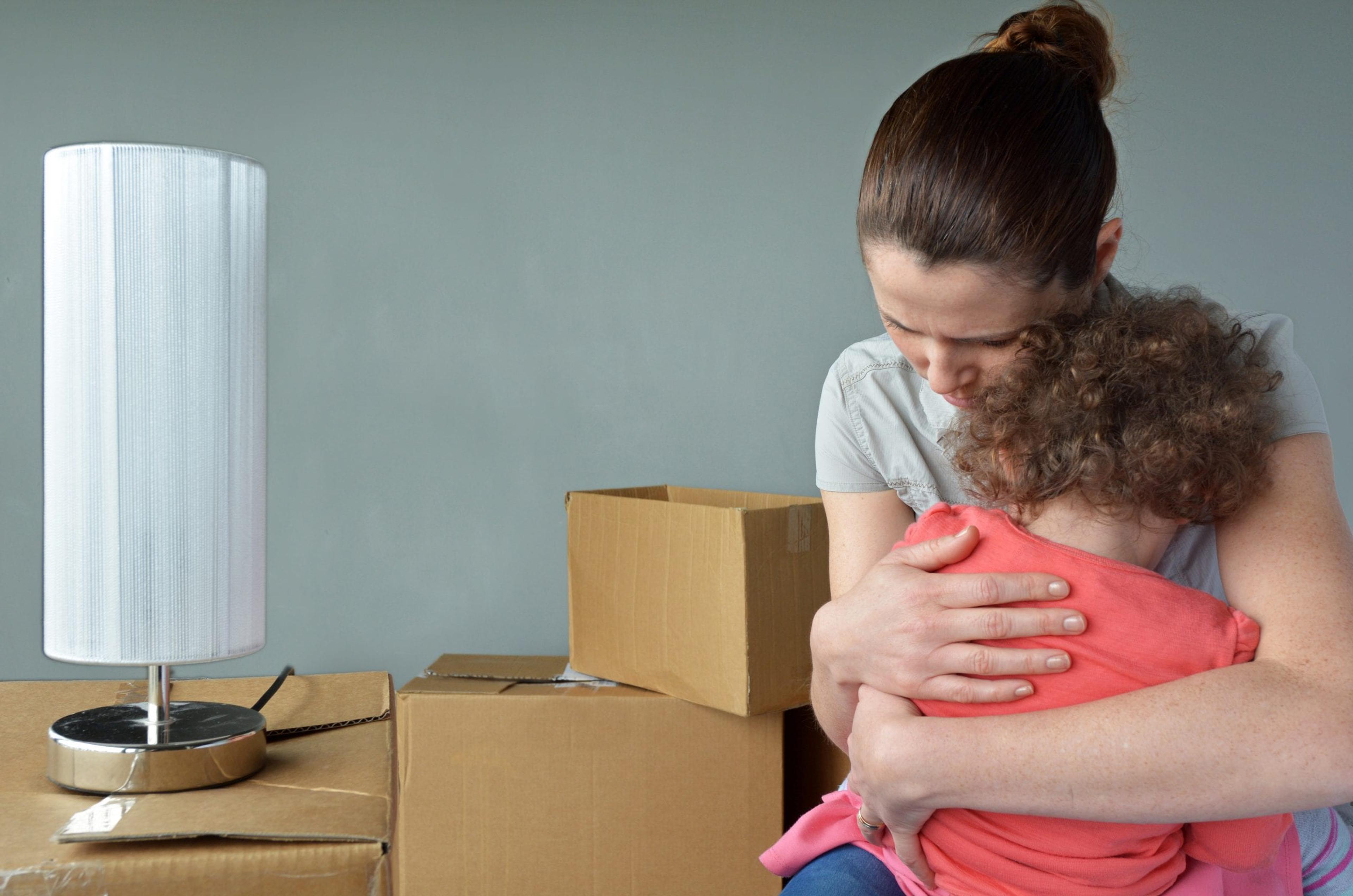 Mom and daughter hugging surrounded by boxes