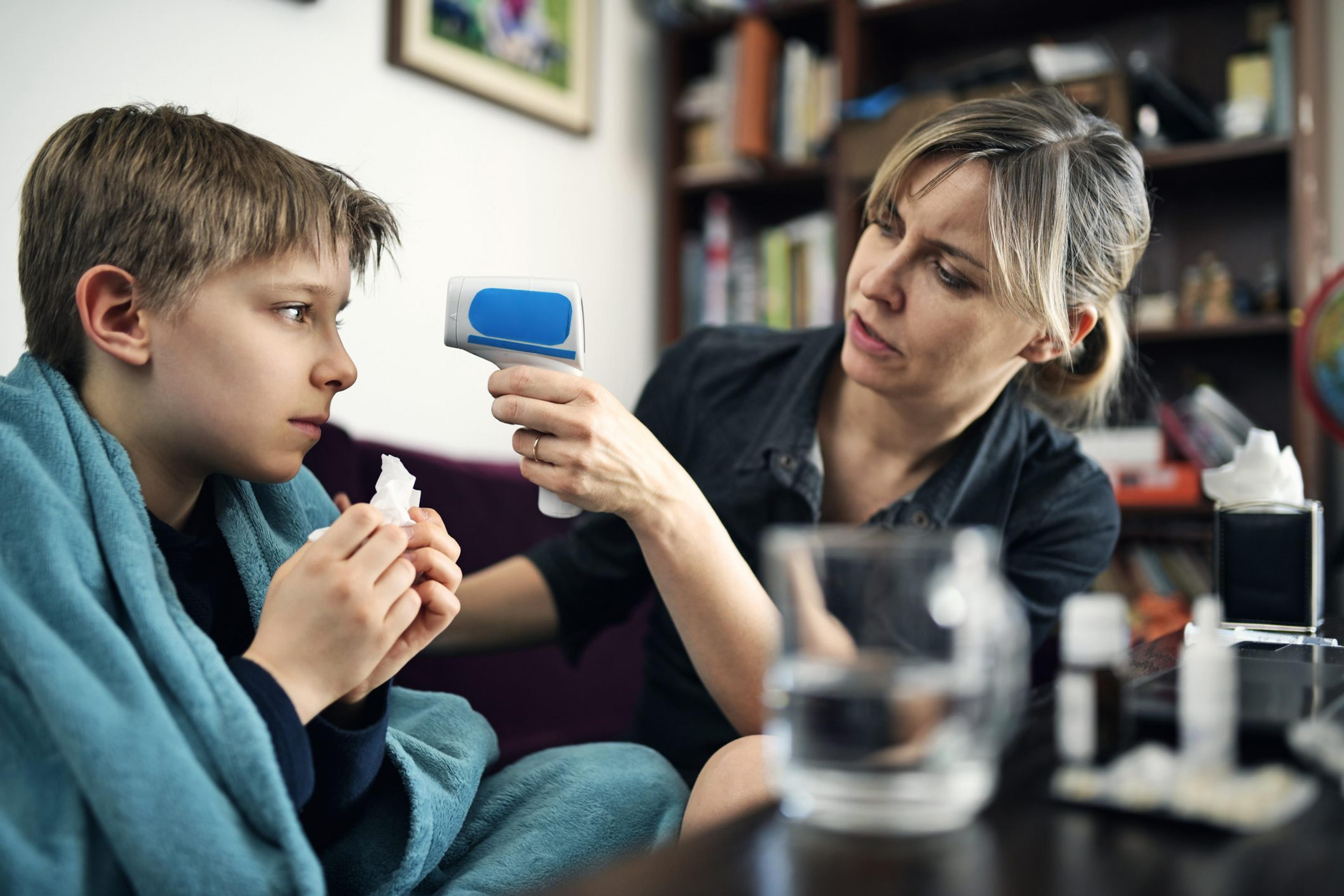 Mother taking sick son's temperature at home